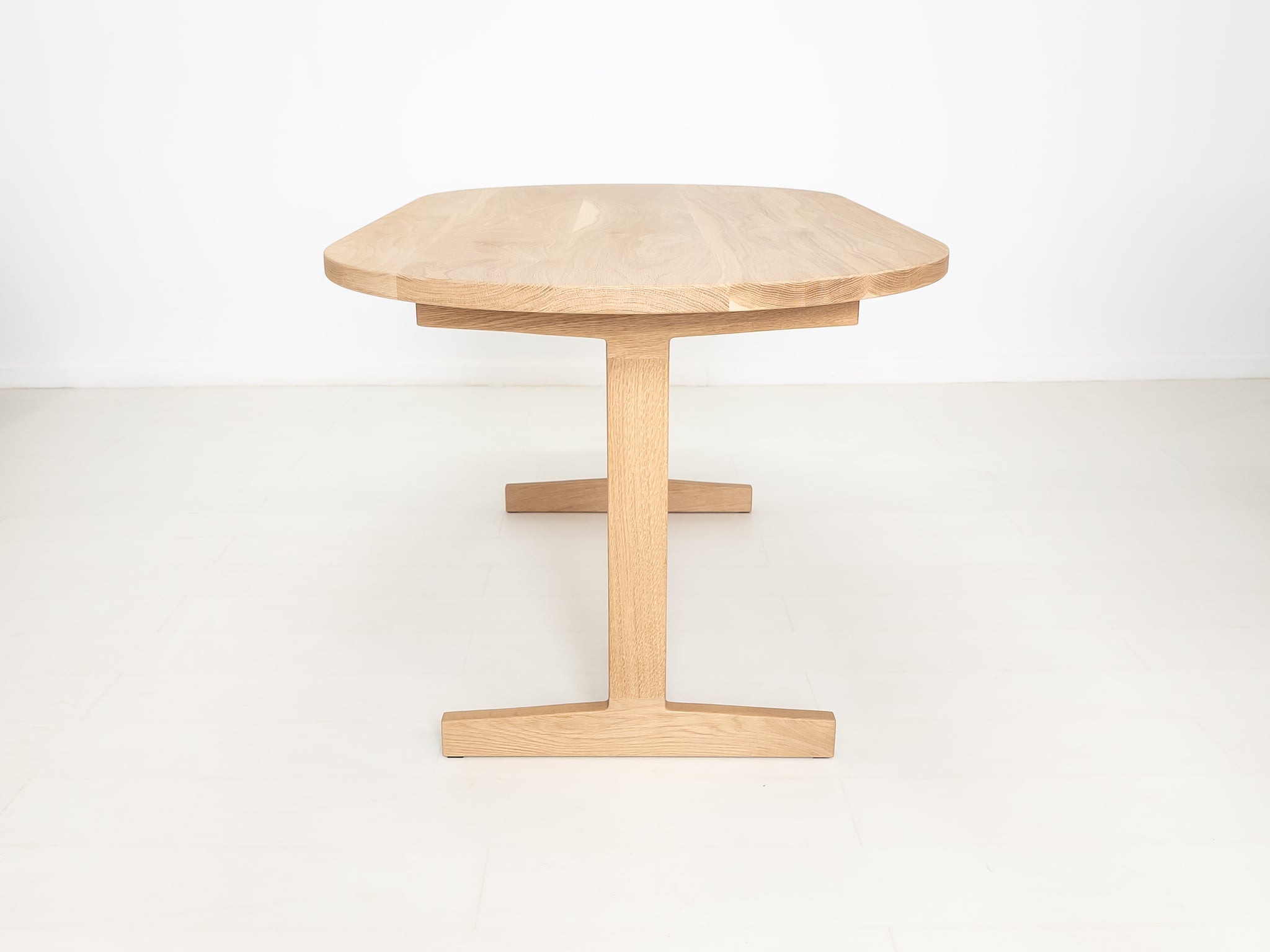 Custom wood dining table with clean lines and trestle base, shown in natural white oak.