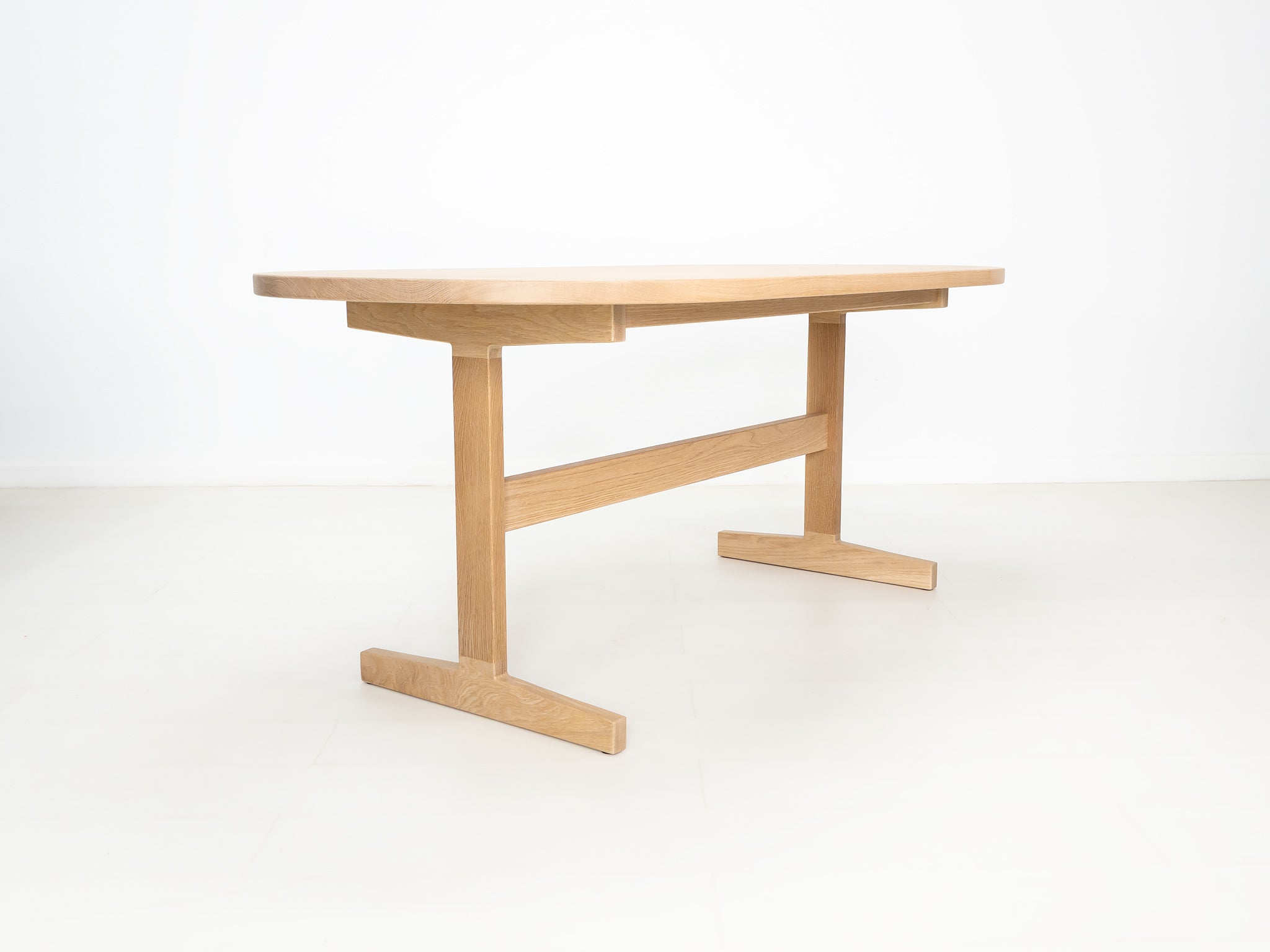 BANQ dining table in natural white oak with trestle base.