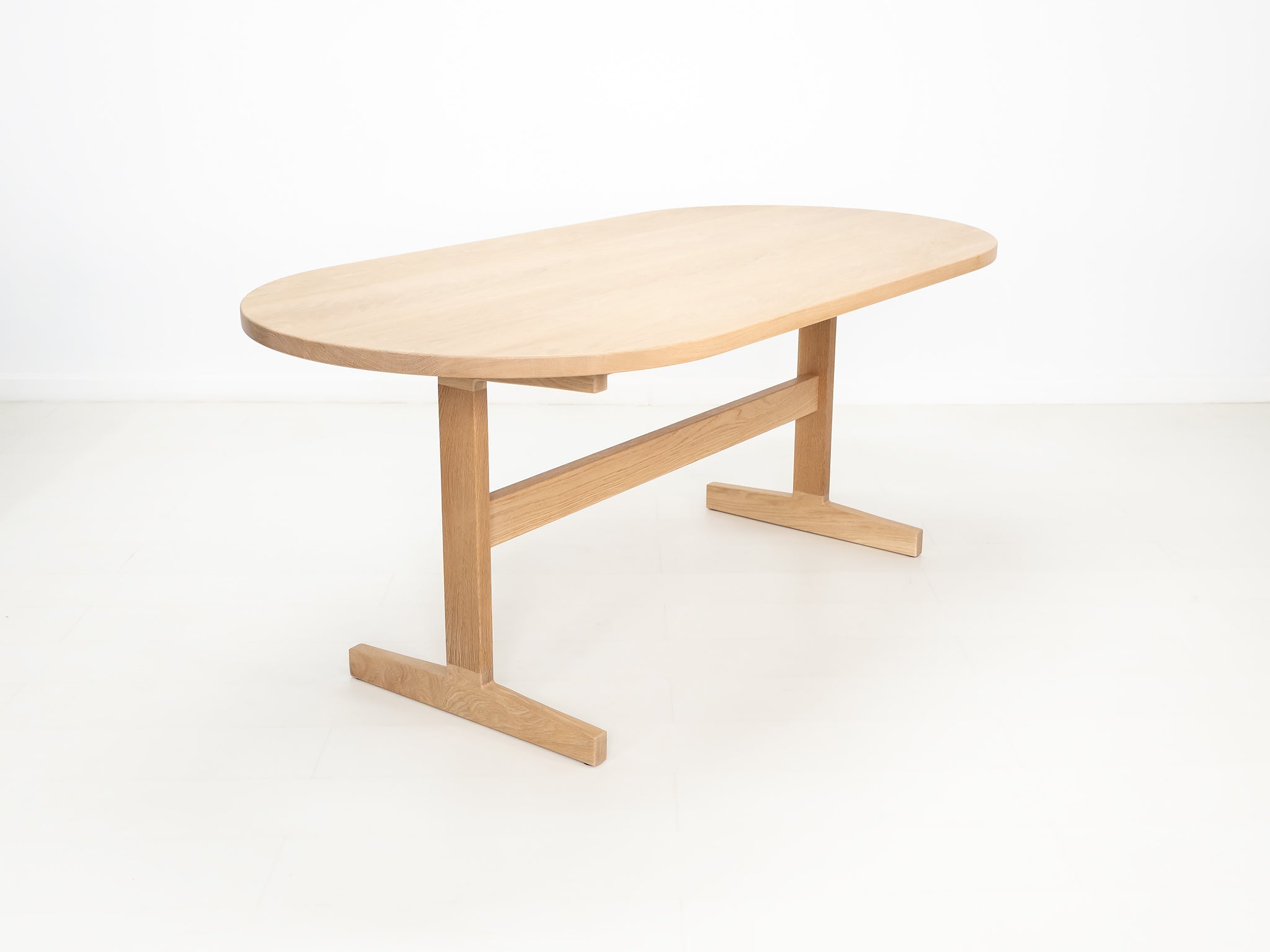 BANQ dining table in natural white oak with trestle base.