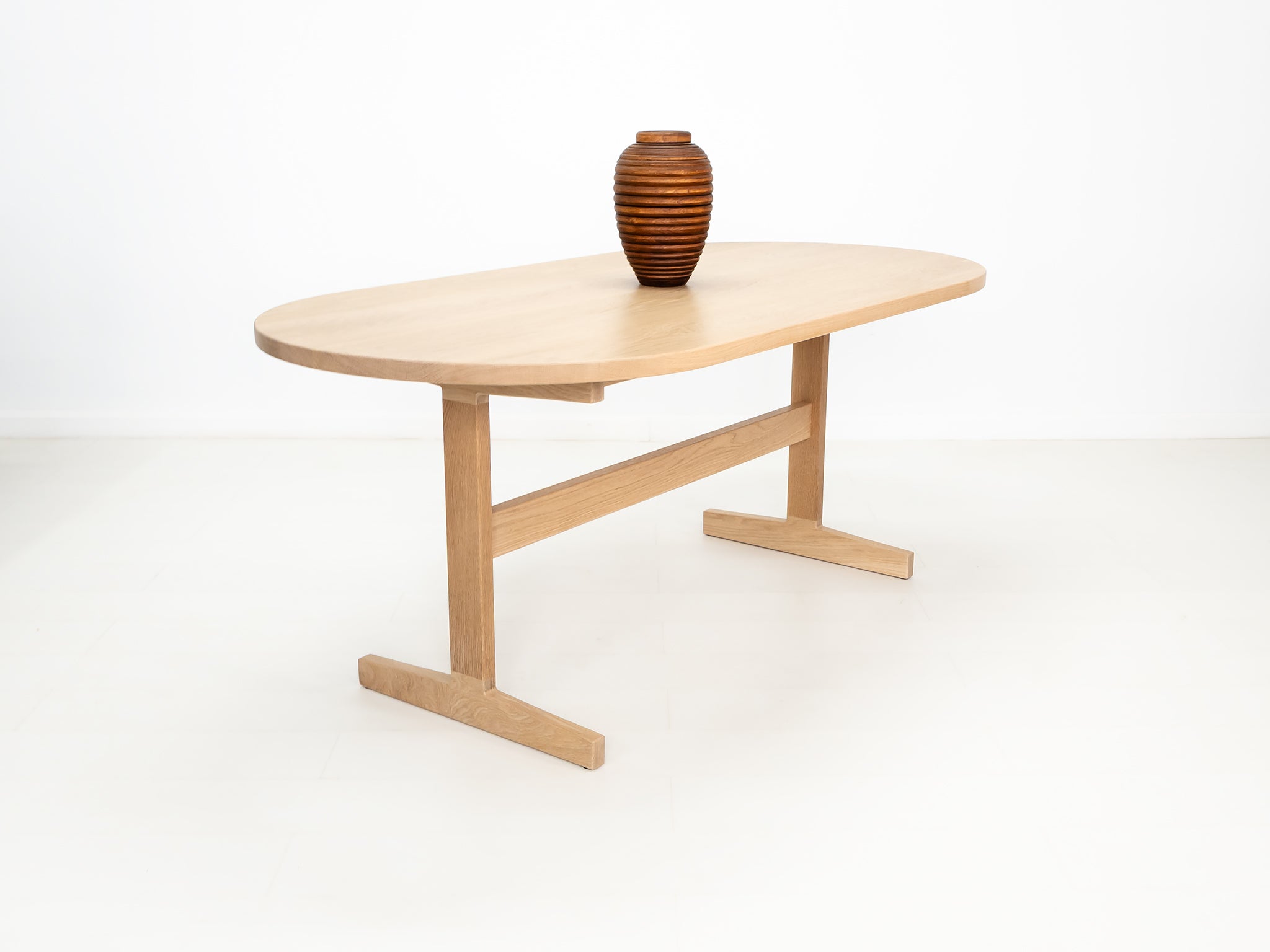 BANQ dining table in natural white oak with trestle base.