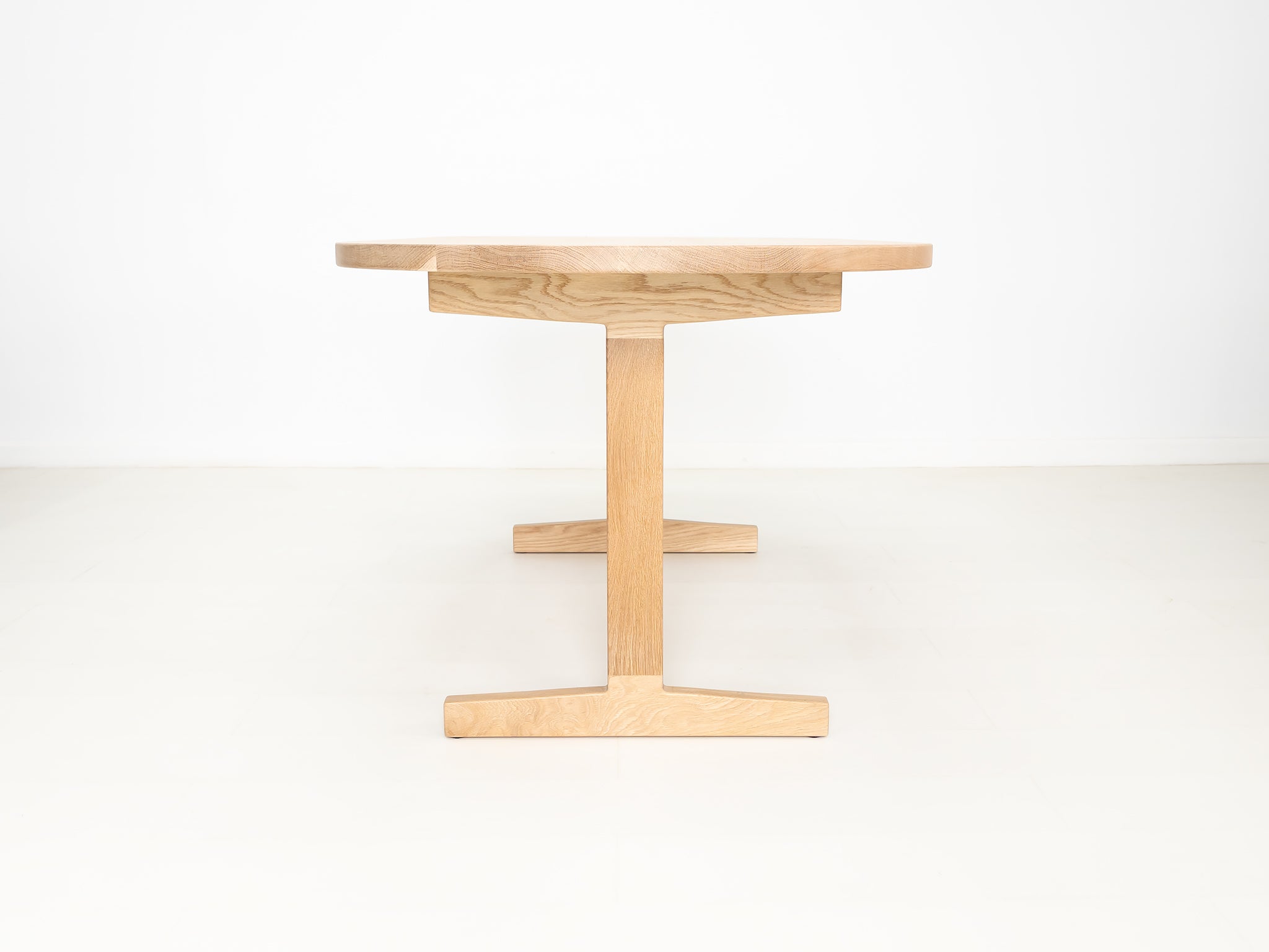 BANQ dining table in natural white oak with trestle base.