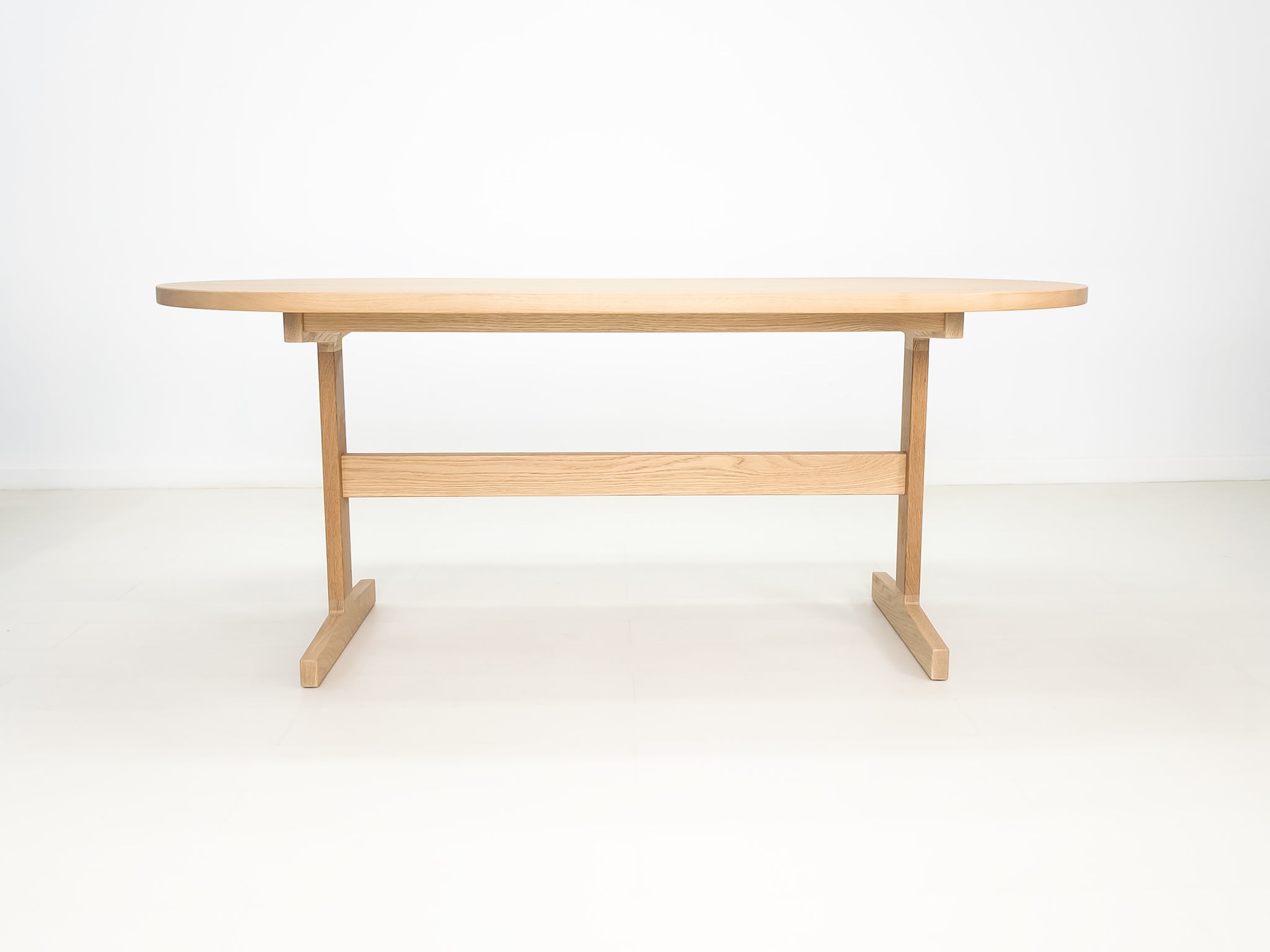 BANQ dining table in natural white oak with trestle base.