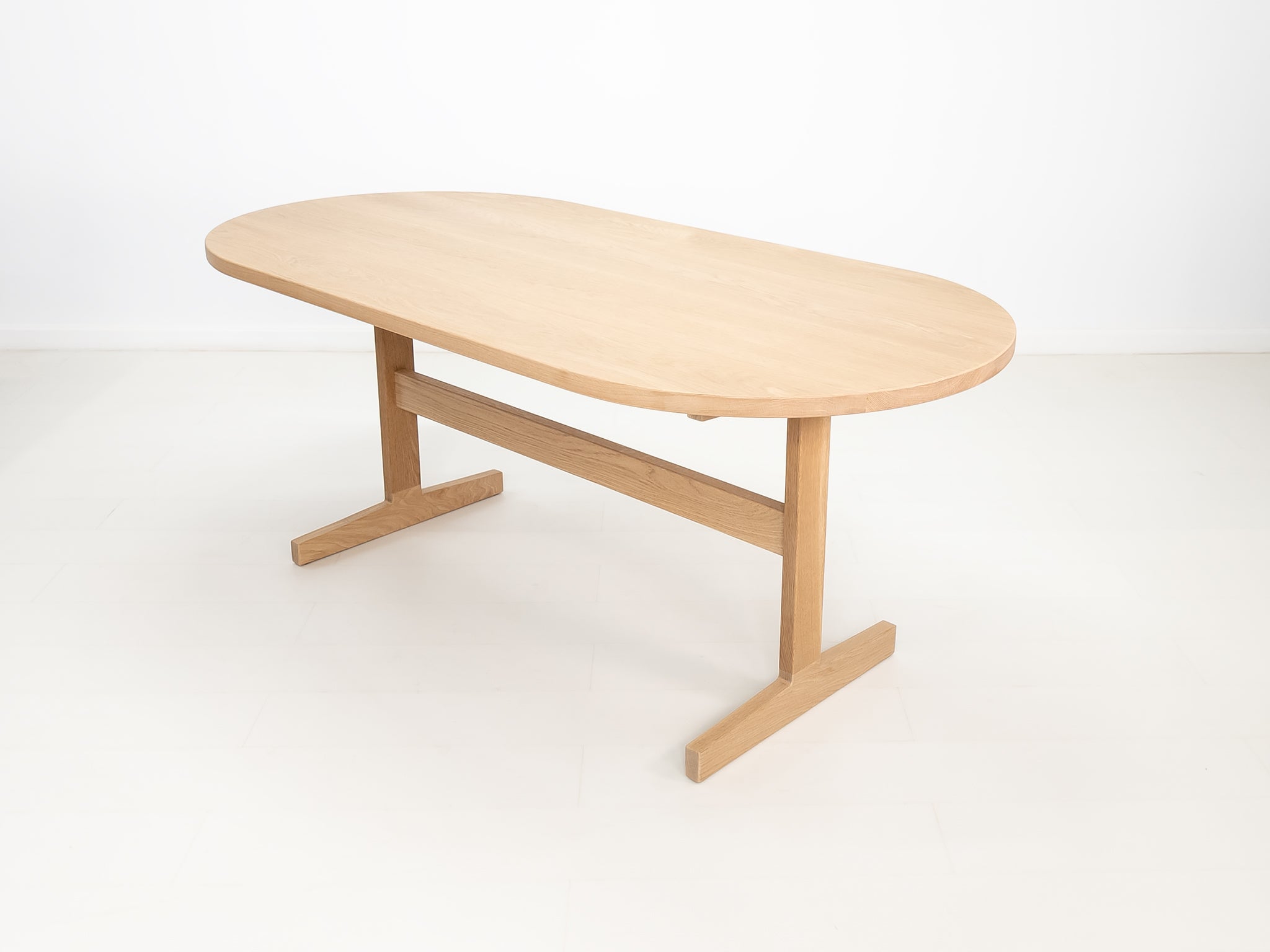 BANQ dining table in natural white oak with trestle base.
