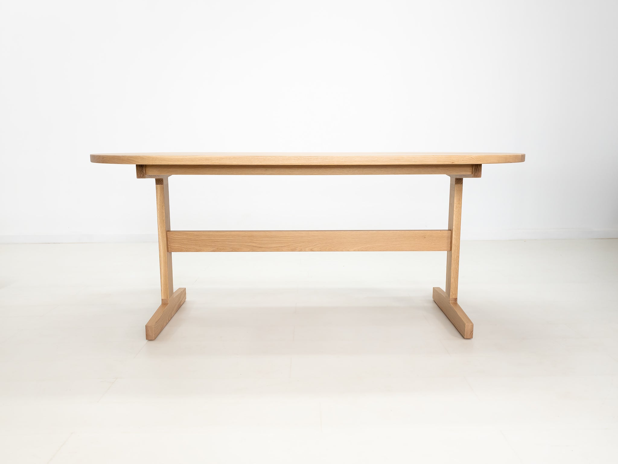 BANQ dining table in natural white oak with trestle base.