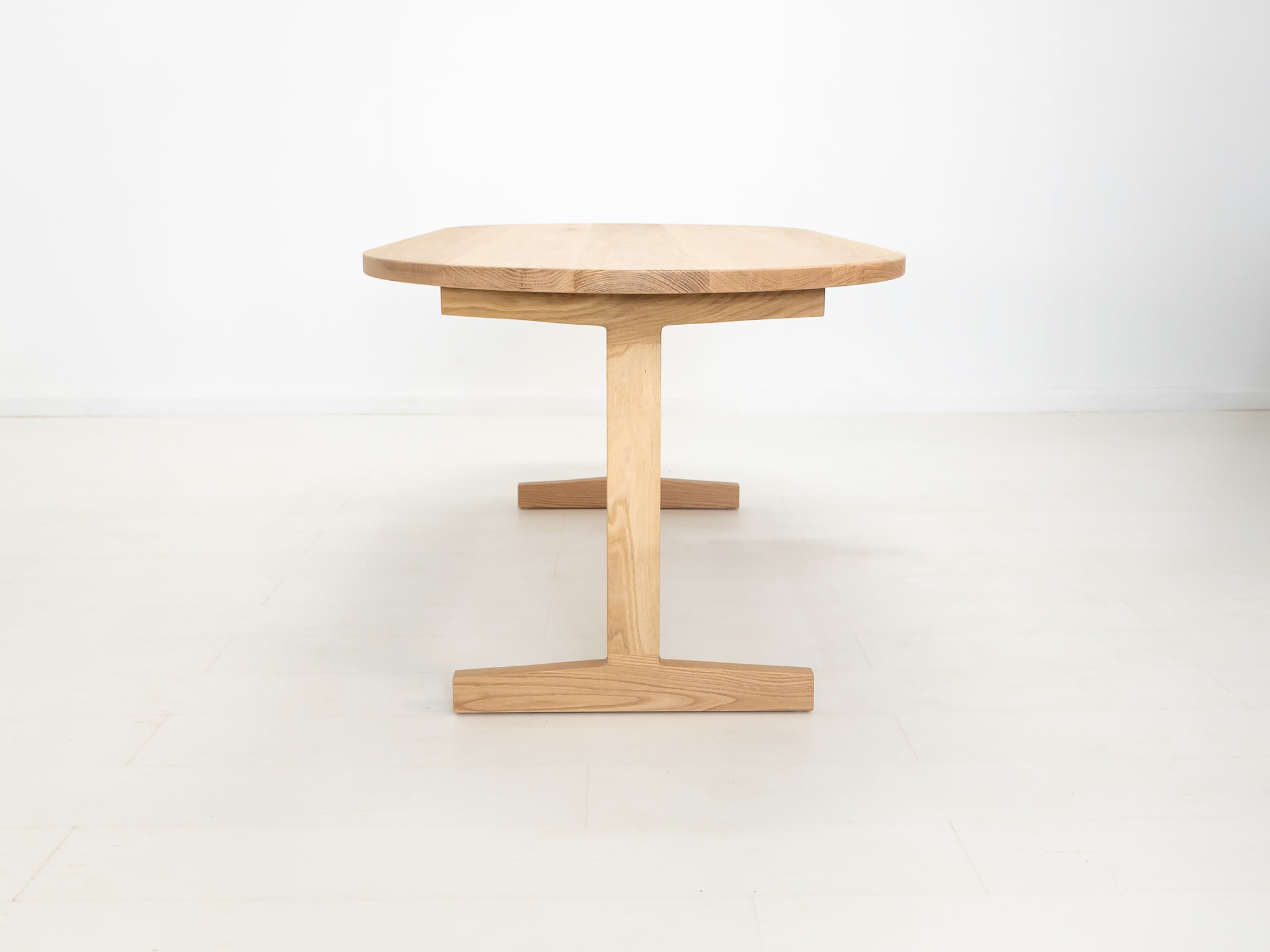 BANQ dining table in natural white oak with trestle base.