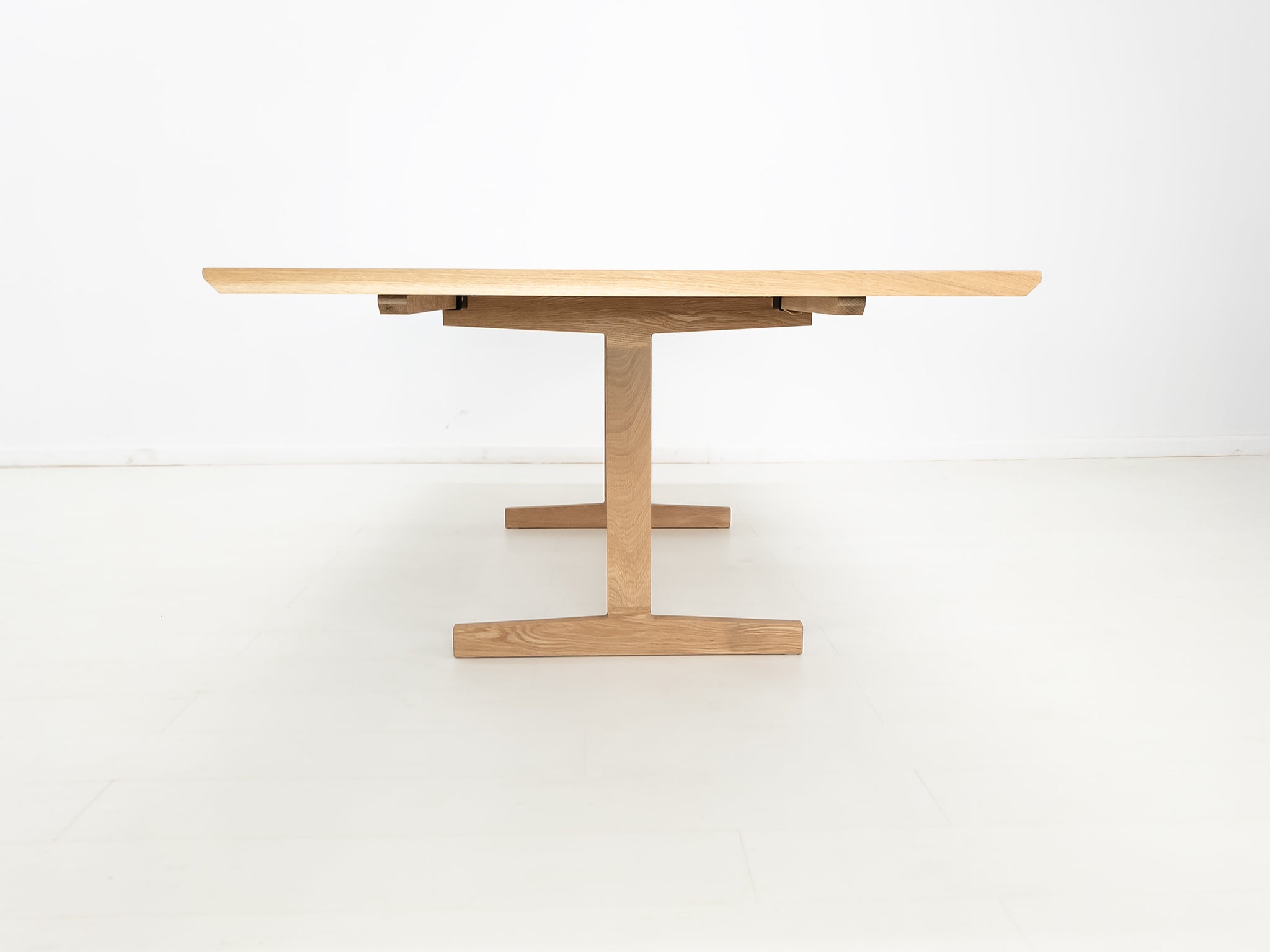 BRIT trestle dining table in natural white oak, shown with beveled edge top.