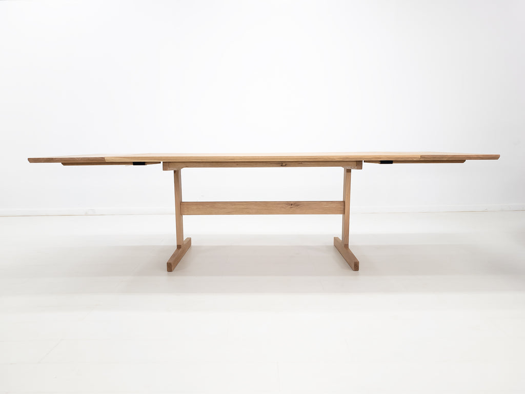 BRIT trestle dining table in natural white oak, shown with beveled edge top and clear matte finish.