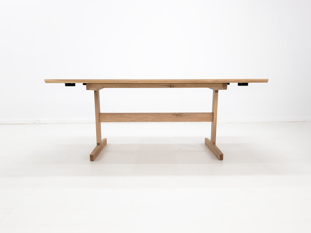 BRIT trestle dining table in natural white oak, shown with beveled edge top and clear matte finish.