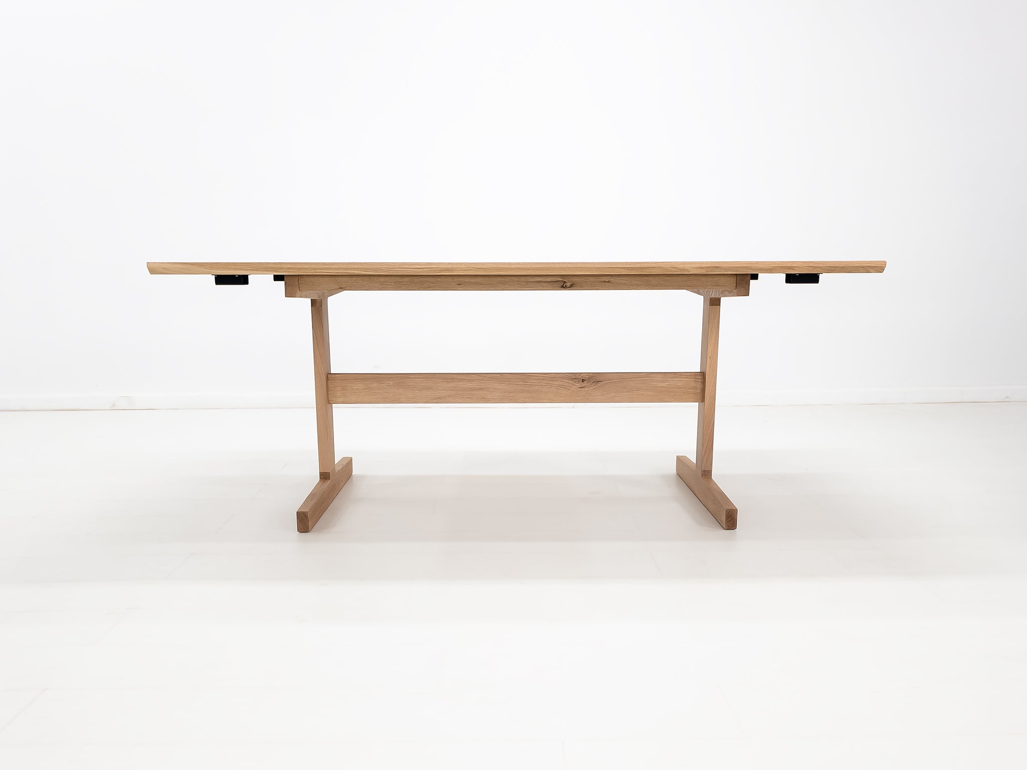 BRIT trestle dining table in natural white oak, shown with beveled edge top and clear matte finish.