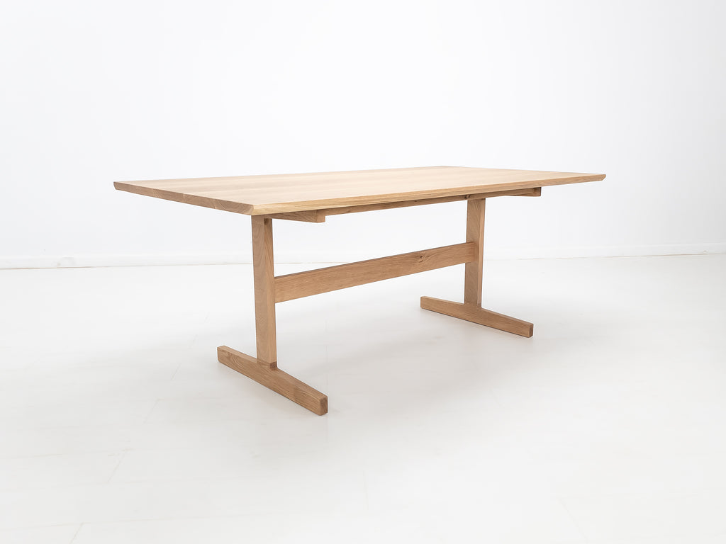 BRIT trestle dining table in natural white oak, shown with beveled edge top and clear matte finish.