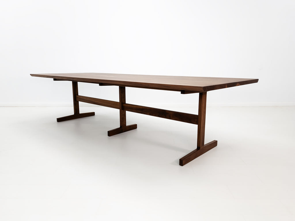Angled view of oiled walnut BRIT table in white studio setting.