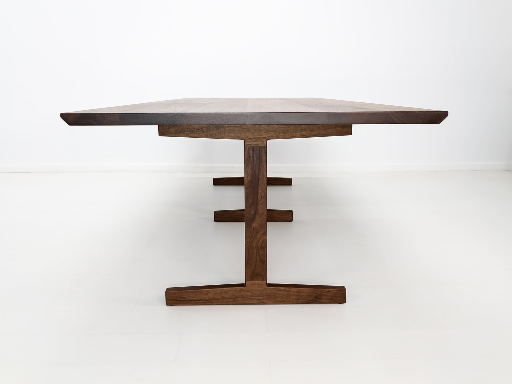View of oiled walnut BRIT table in white studio setting.