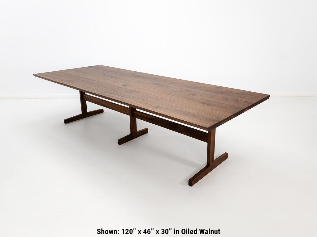 BRIT trestle dining table in oiled walnut, shown with beveled edge top and hardwax oil finish.