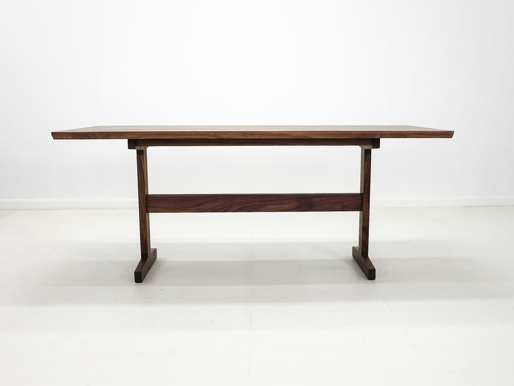 Walnut trestle table with smooth, hand-finished edge.