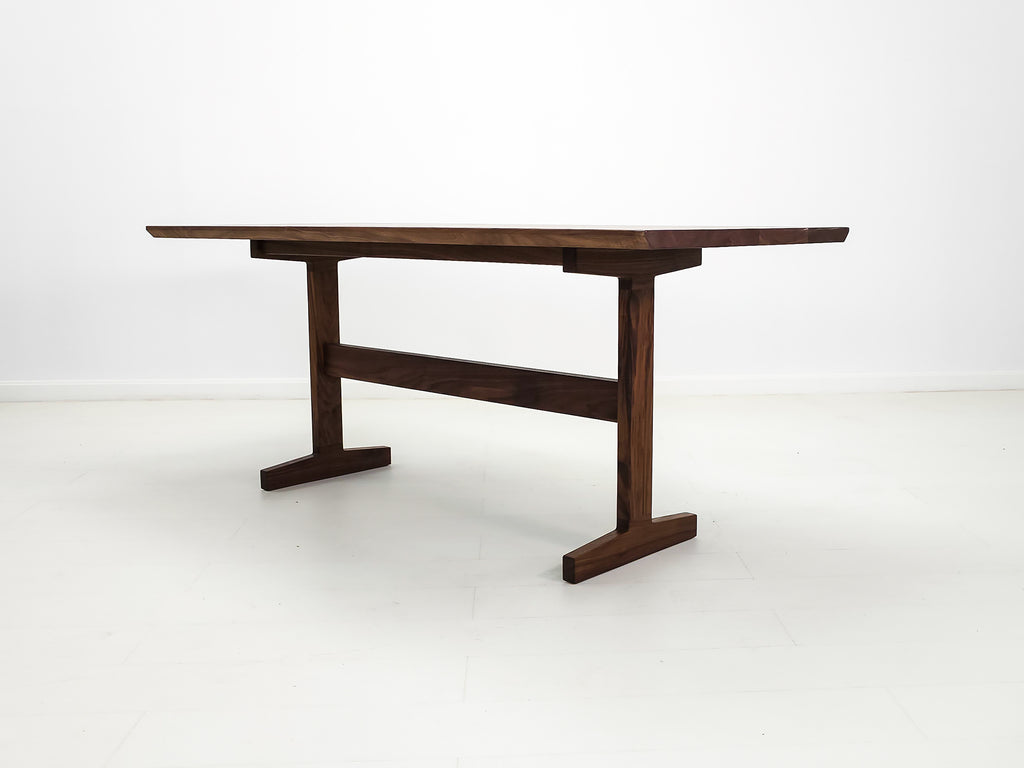 Walnut trestle table with smooth, hand-finished edge.