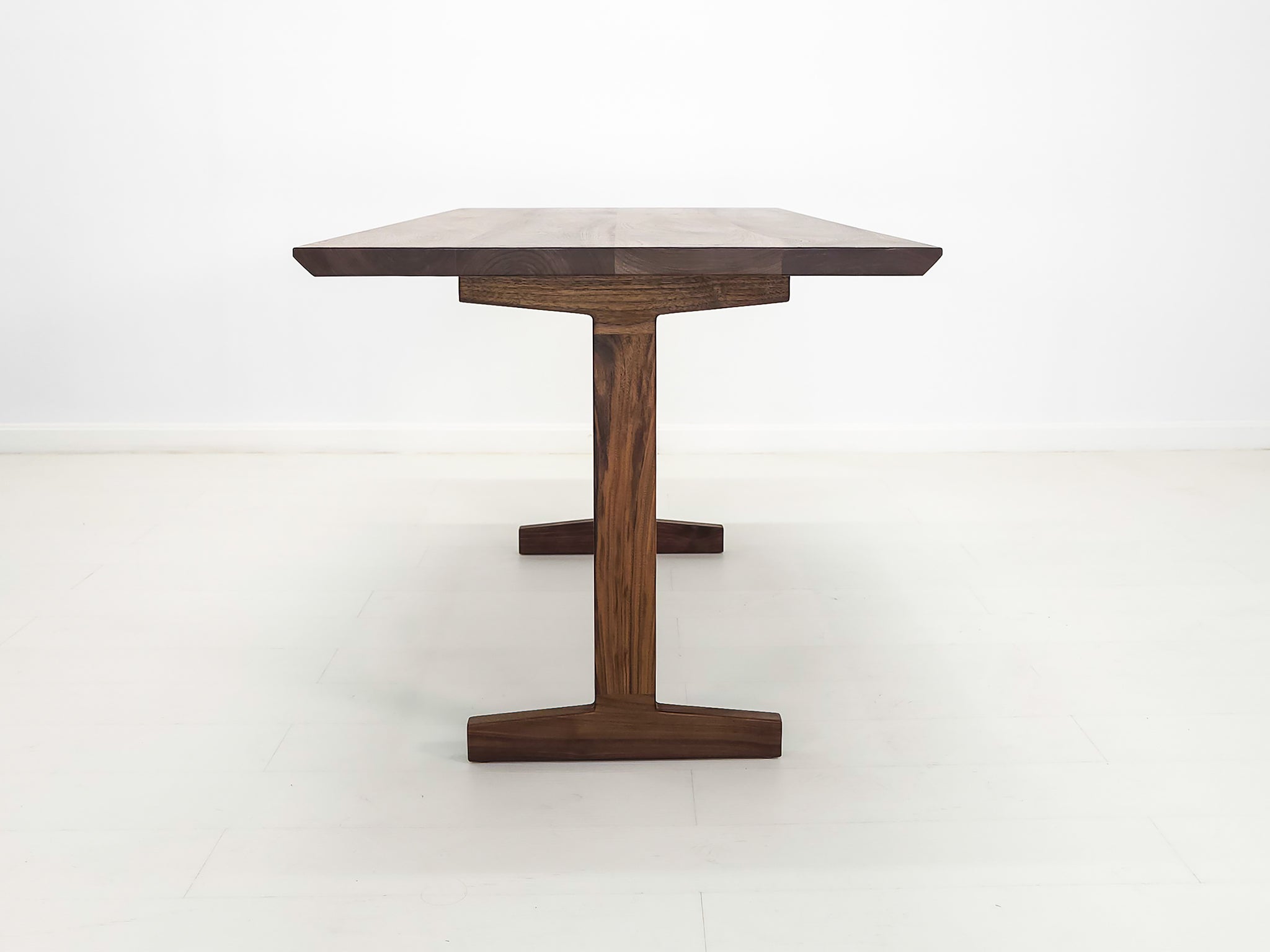 Close-up of beveled walnut tabletop with smooth, hand-finished edge.