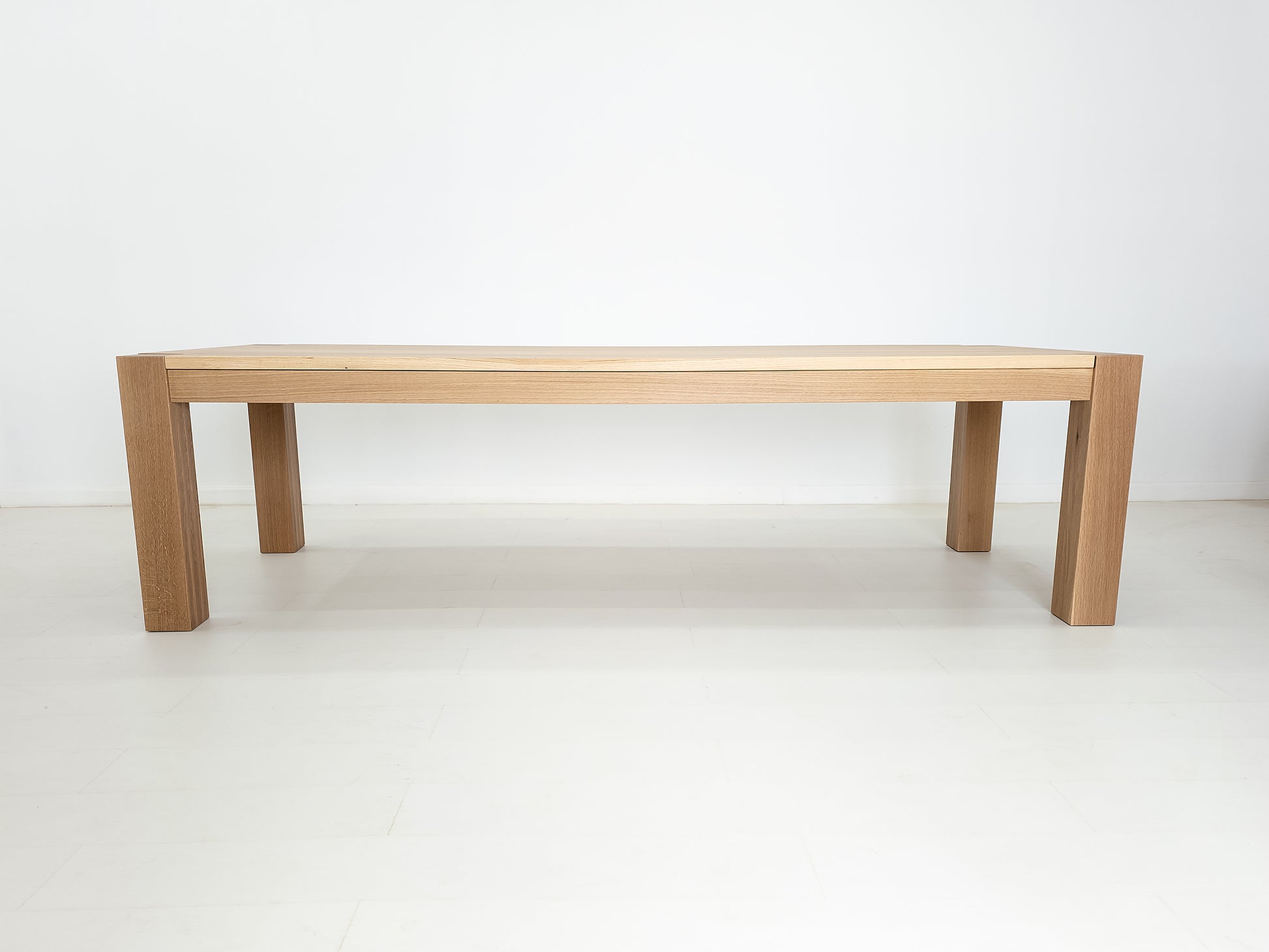 JAQI dining table in solid white oak with breadboard ends and square legs.