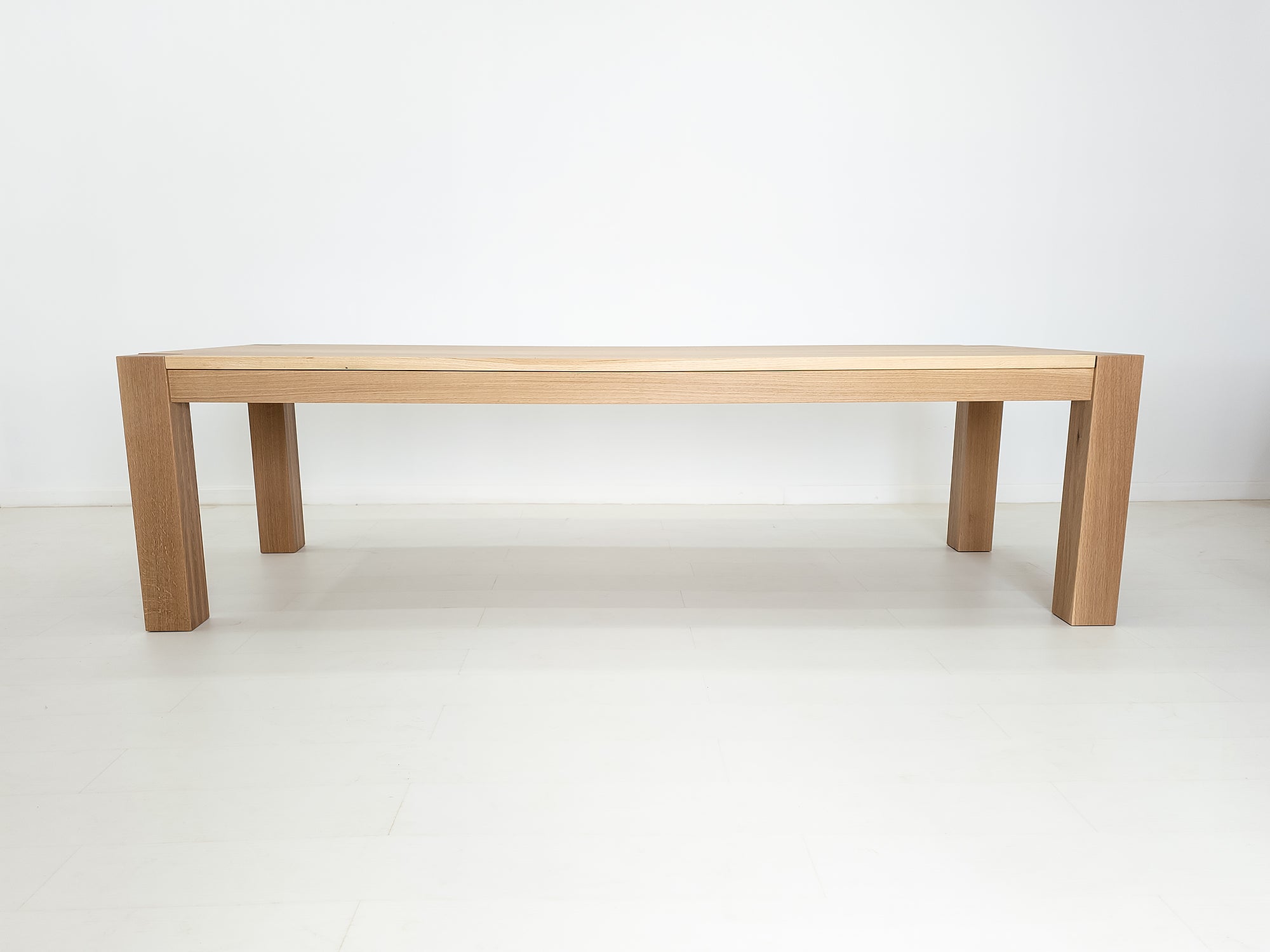 JAQI dining table in solid white oak with breadboard ends and square legs.
