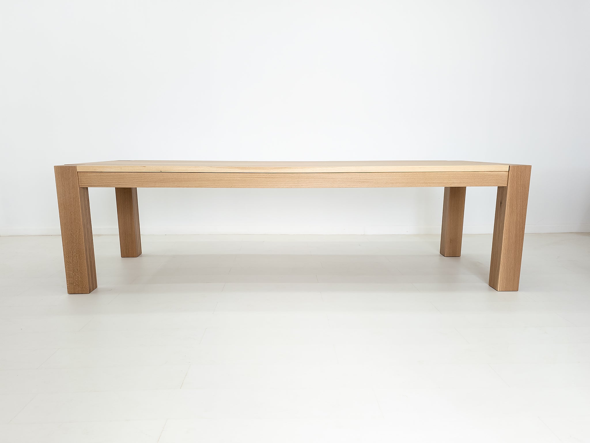 JAQI dining table in solid white oak with breadboard ends and square legs.