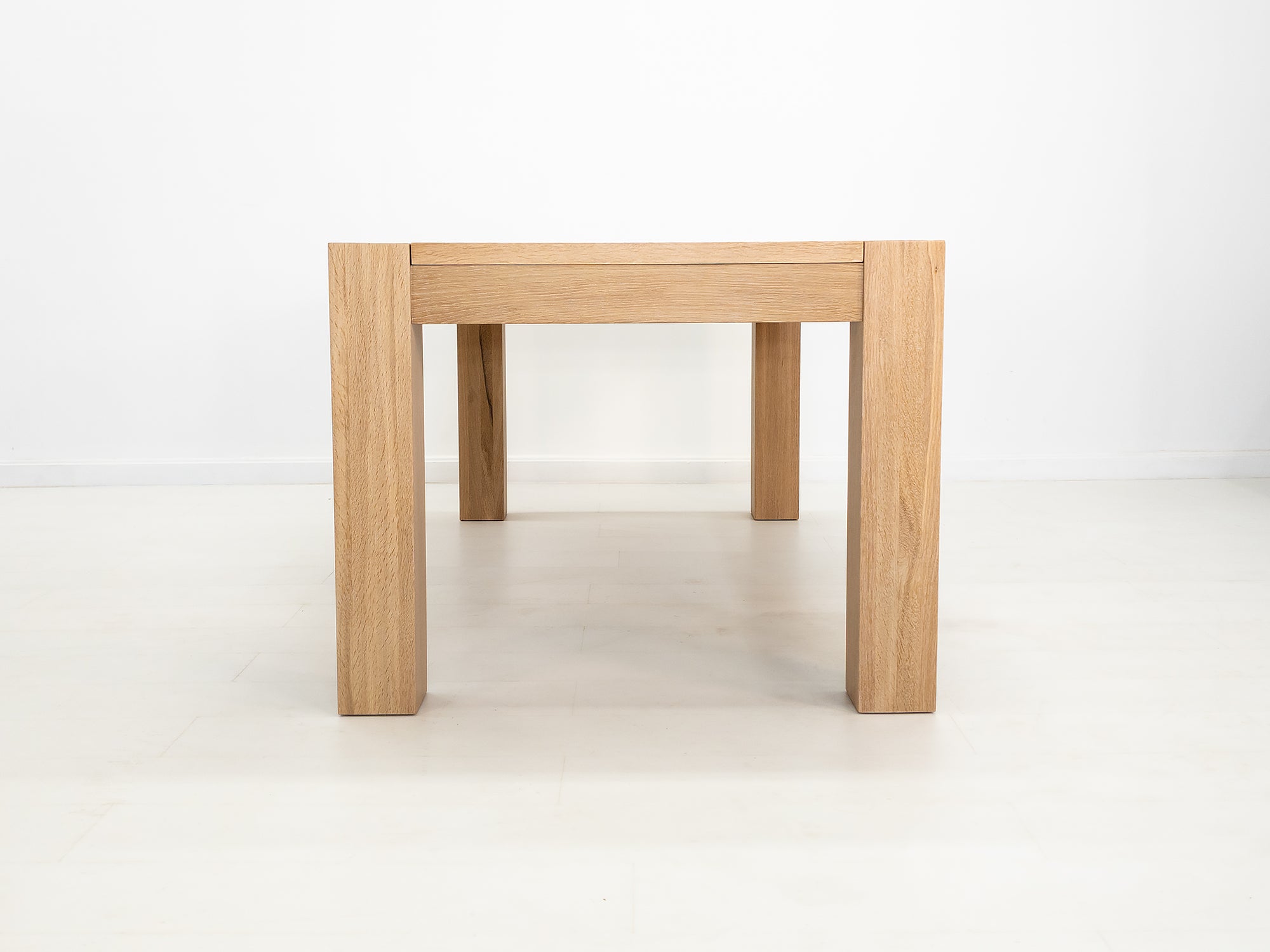 JAQI dining table in solid white oak with breadboard ends and square legs.