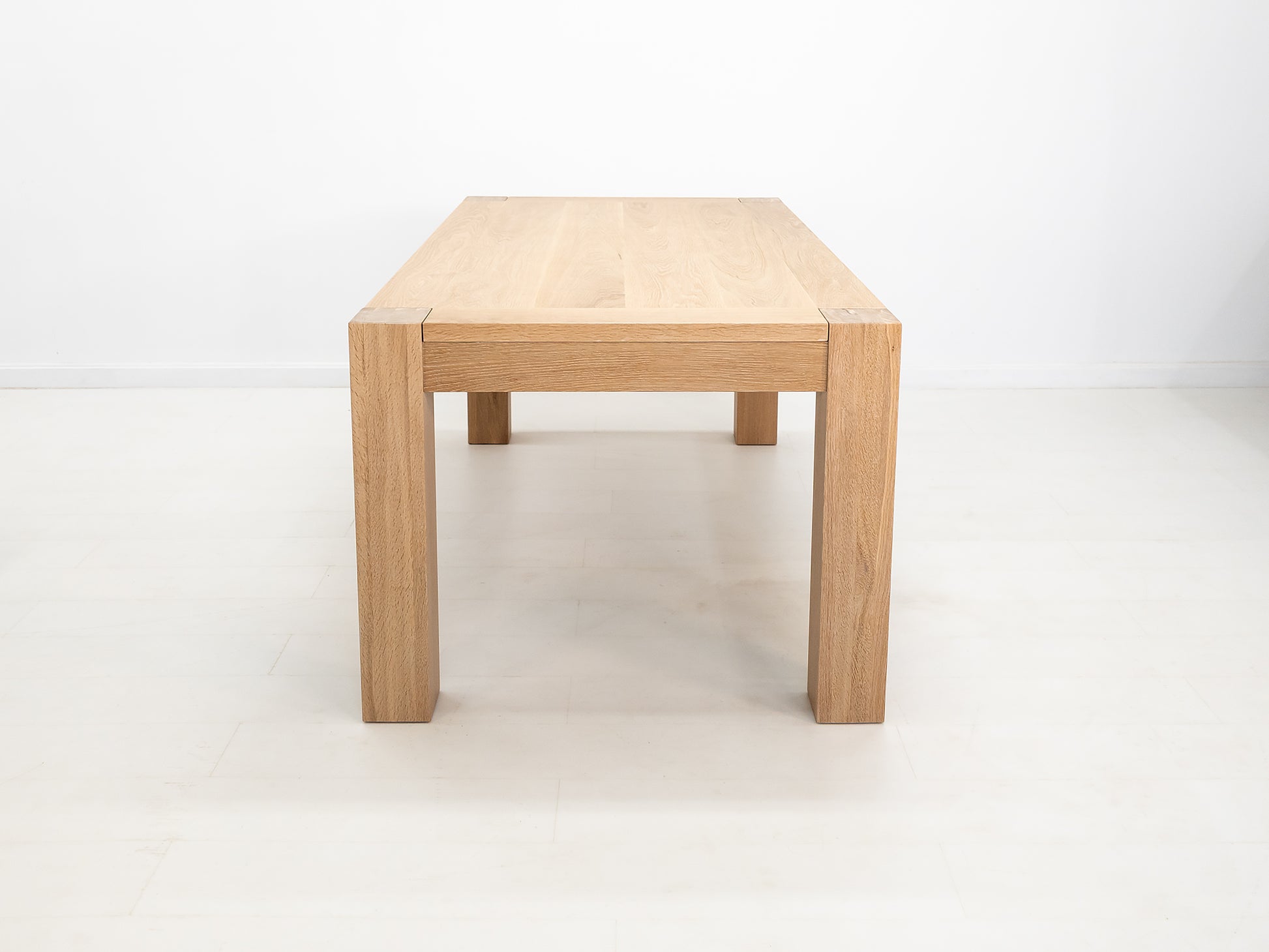 JAQI dining table in solid white oak with breadboard ends and square legs.