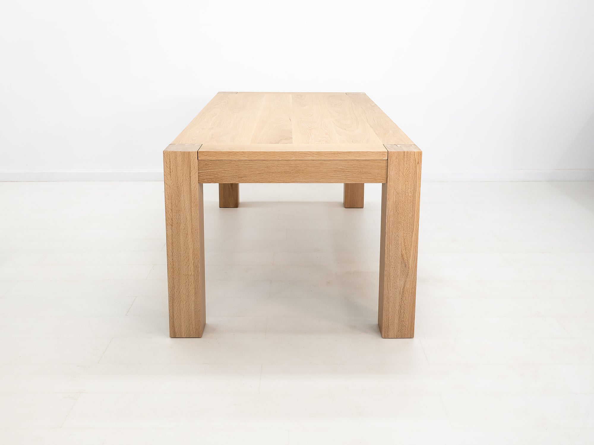 JAQI dining table in solid white oak with breadboard ends and square legs.