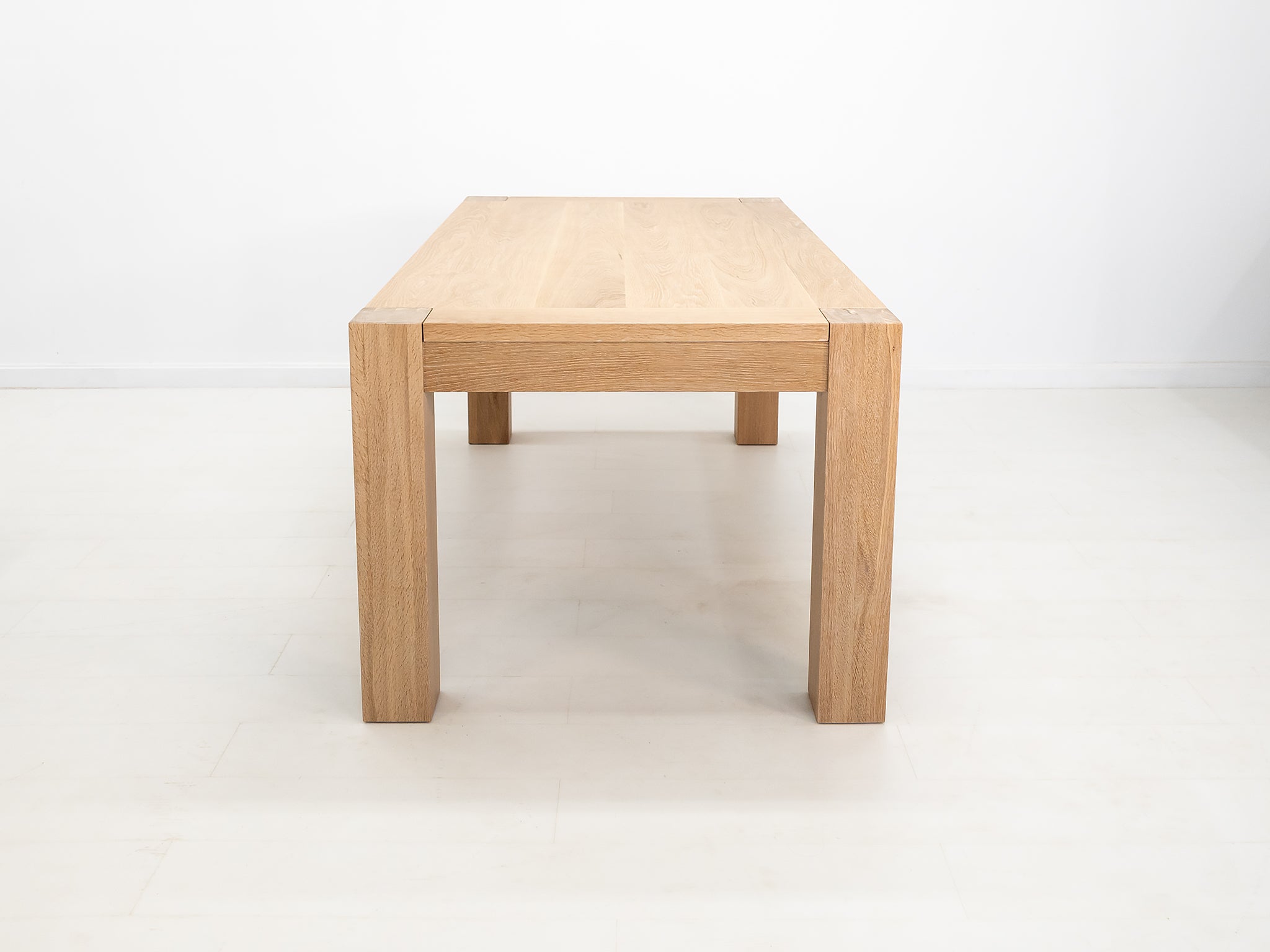 JAQI dining table in solid white oak with breadboard ends and square legs.