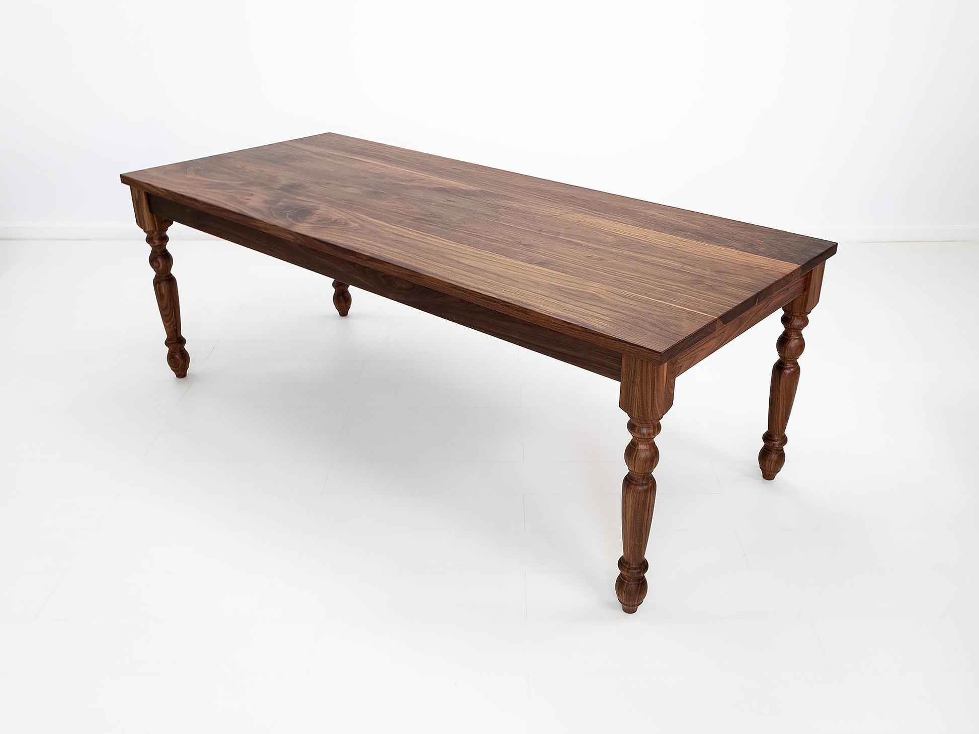 Handcrafted walnut dining table with classic turned legs.