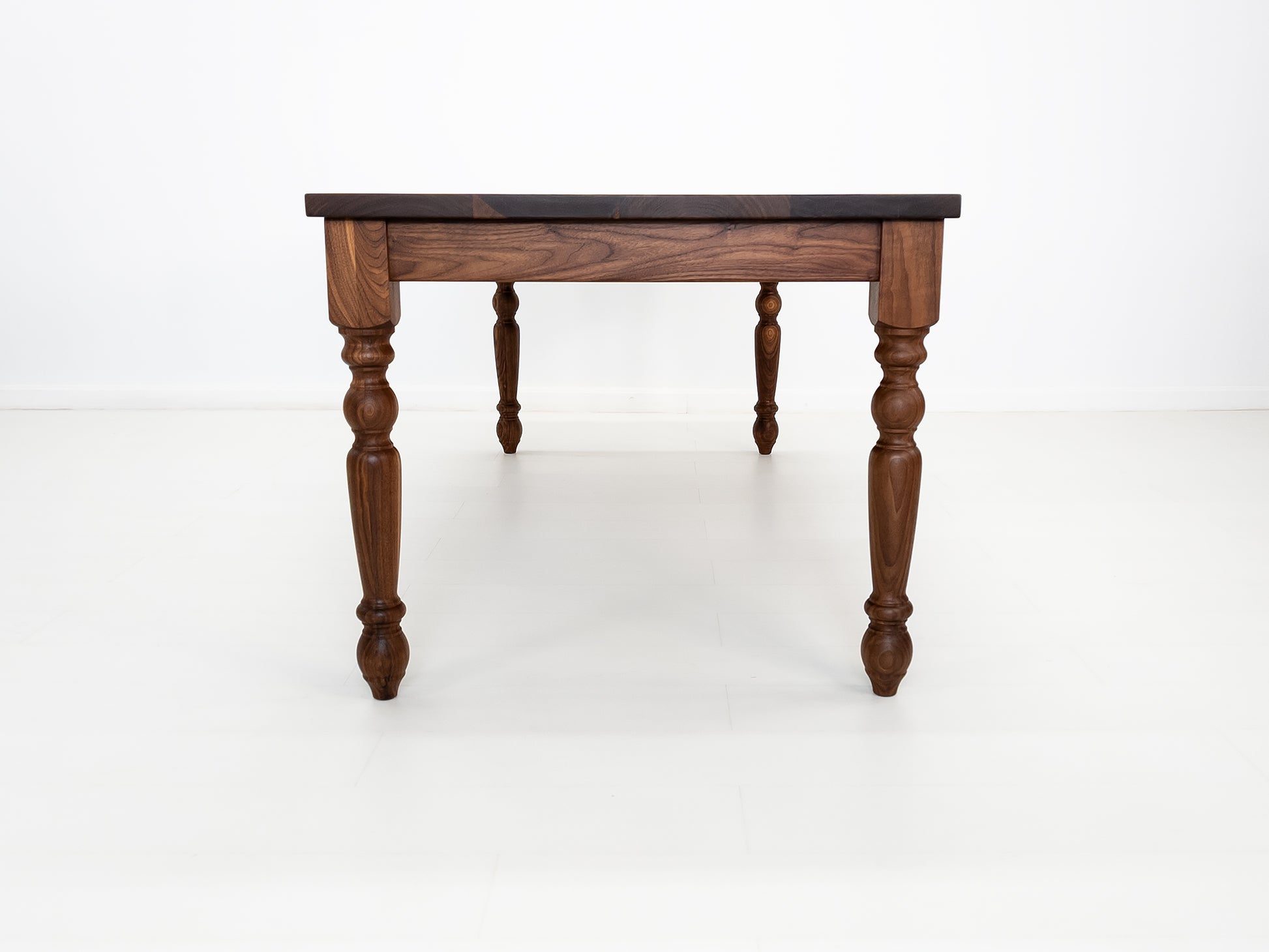 Handcrafted walnut dining table with classic turned legs.