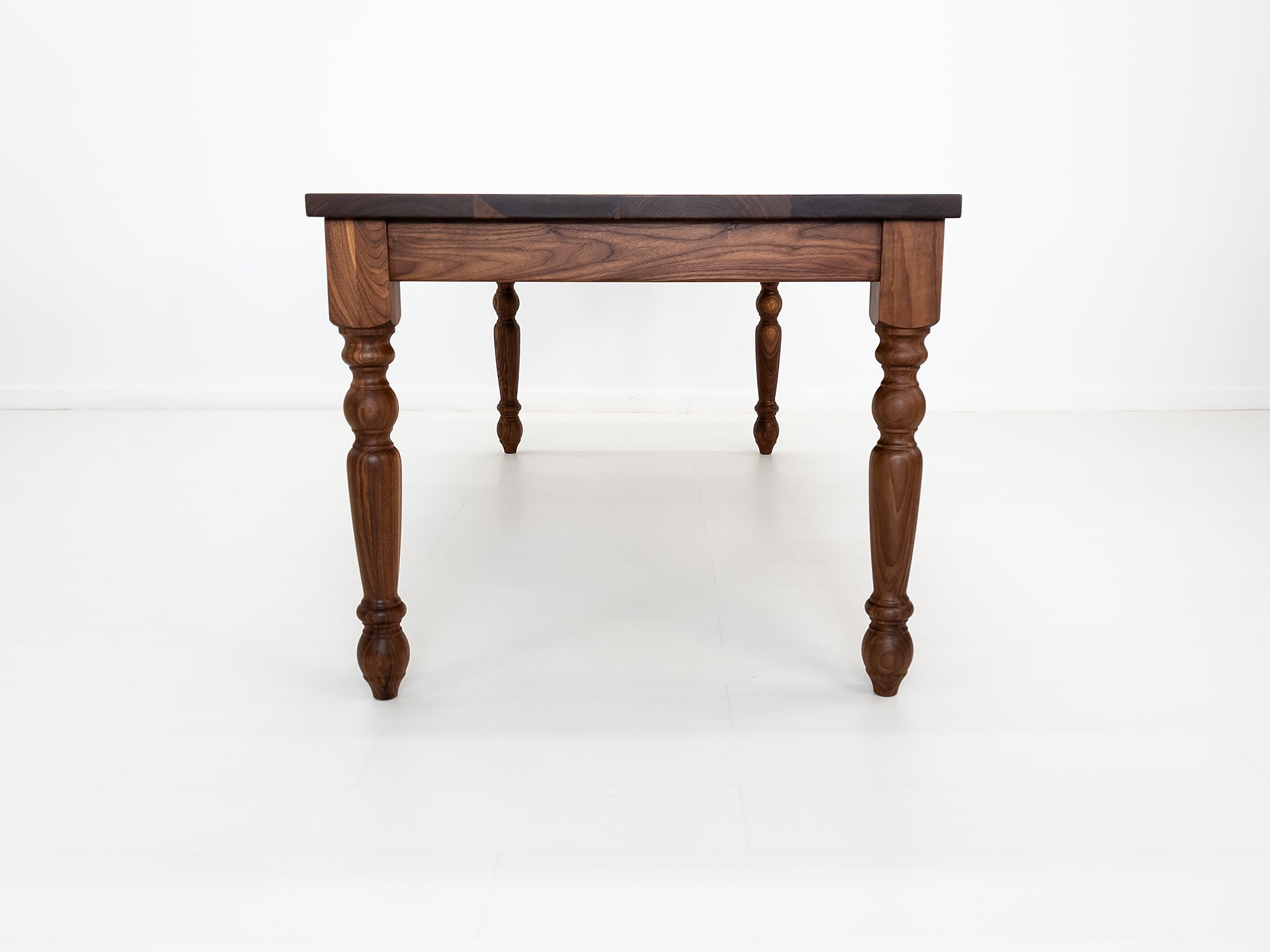 Handcrafted walnut dining table with classic turned legs.