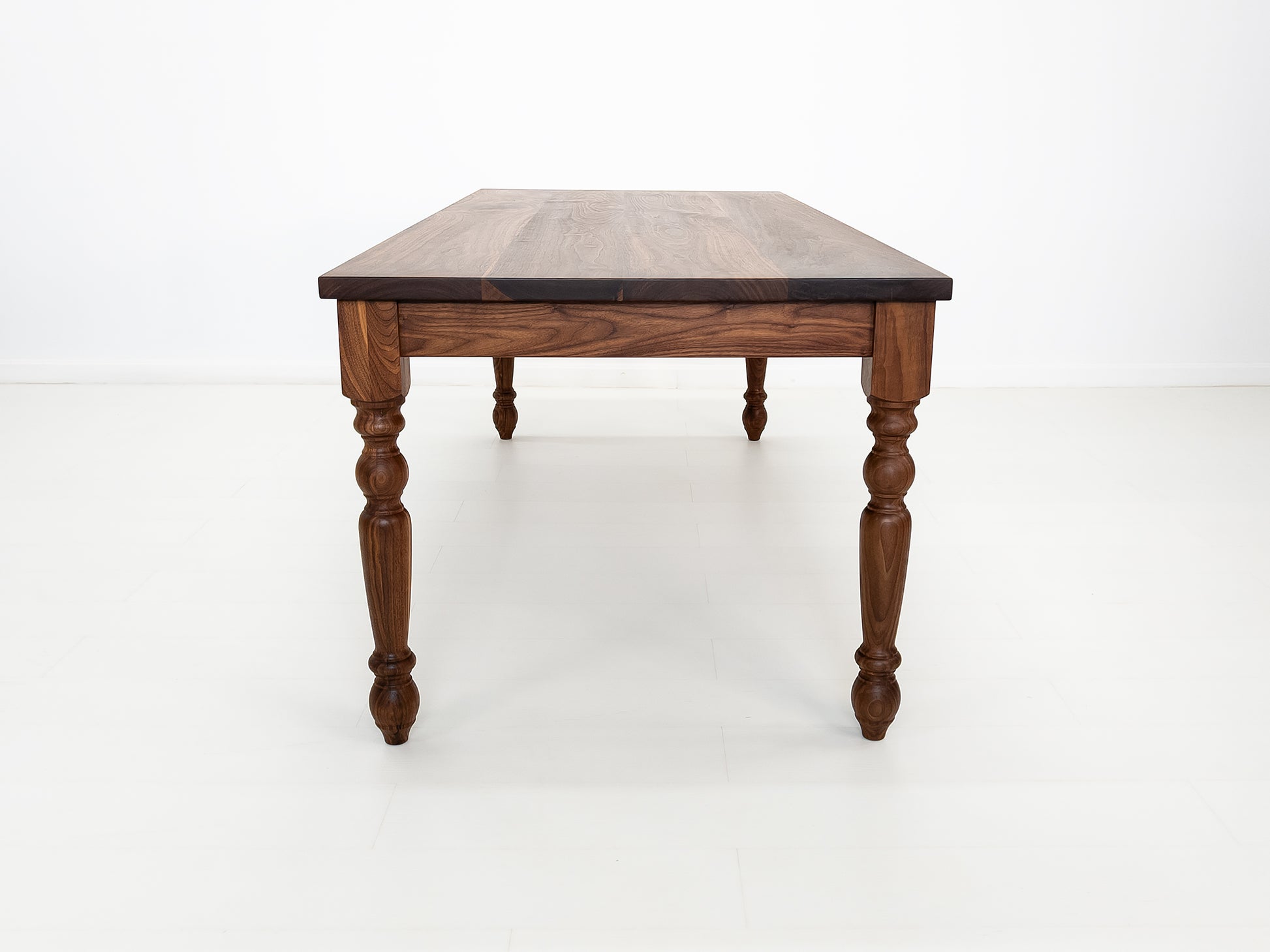 Handcrafted walnut dining table with classic turned legs.