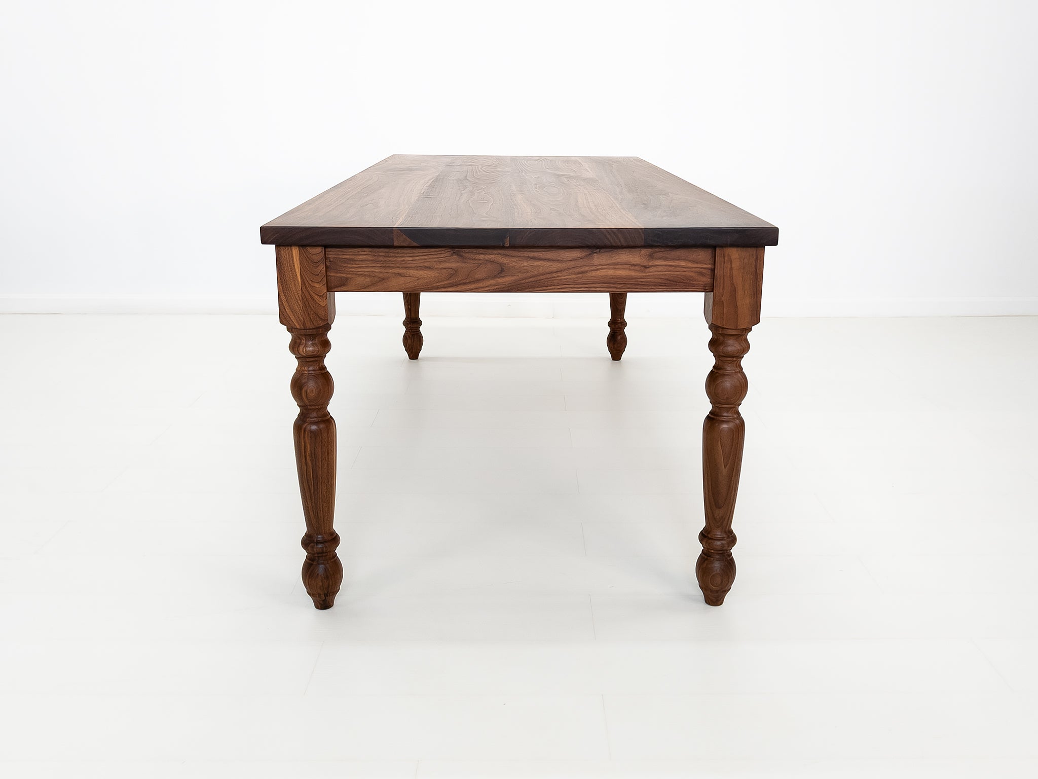 Handcrafted walnut dining table with classic turned legs.