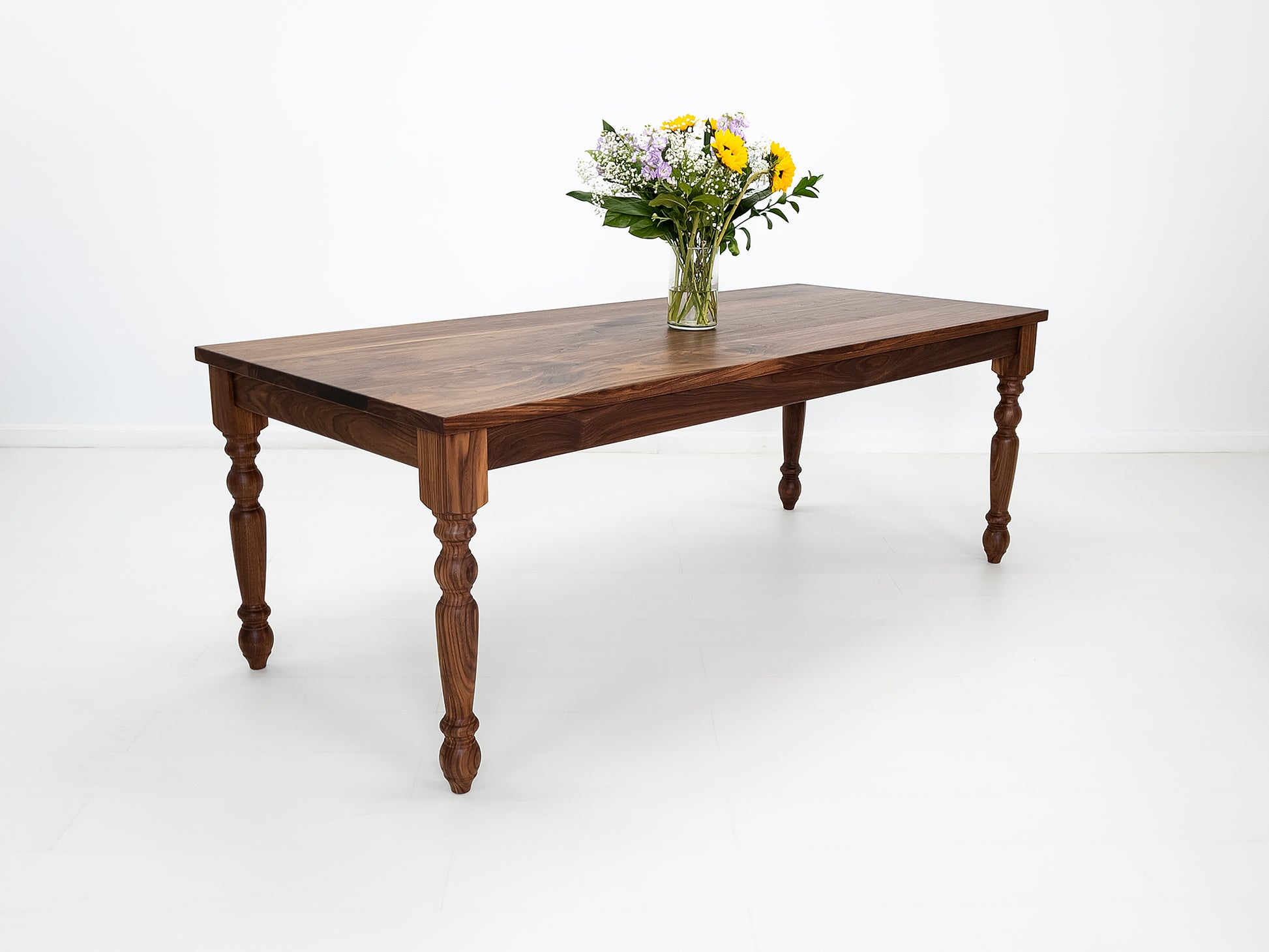 Tess dining table in solid oiled walnut with turned legs and plank-style top.