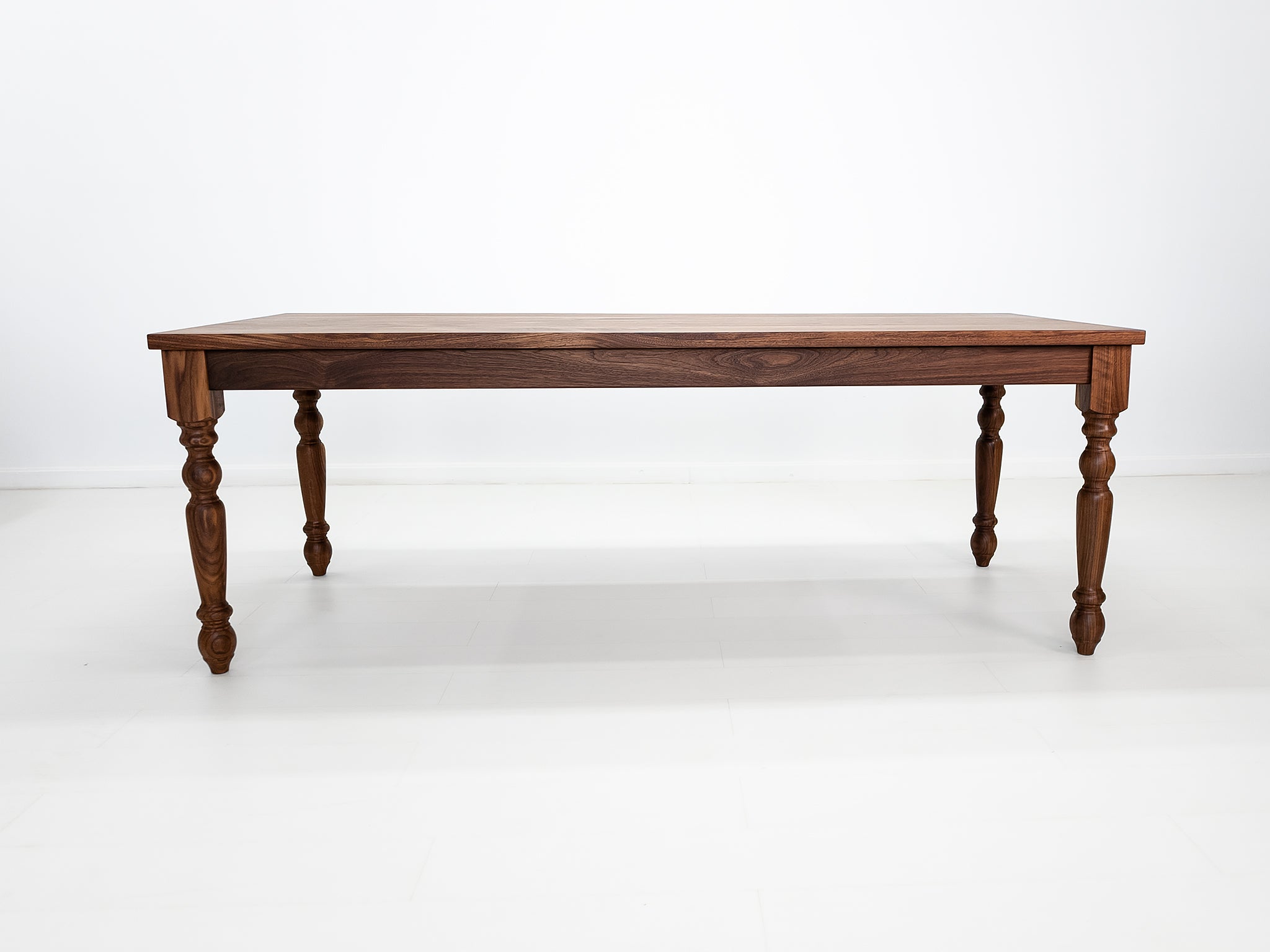 Handcrafted walnut dining table with classic turned legs.