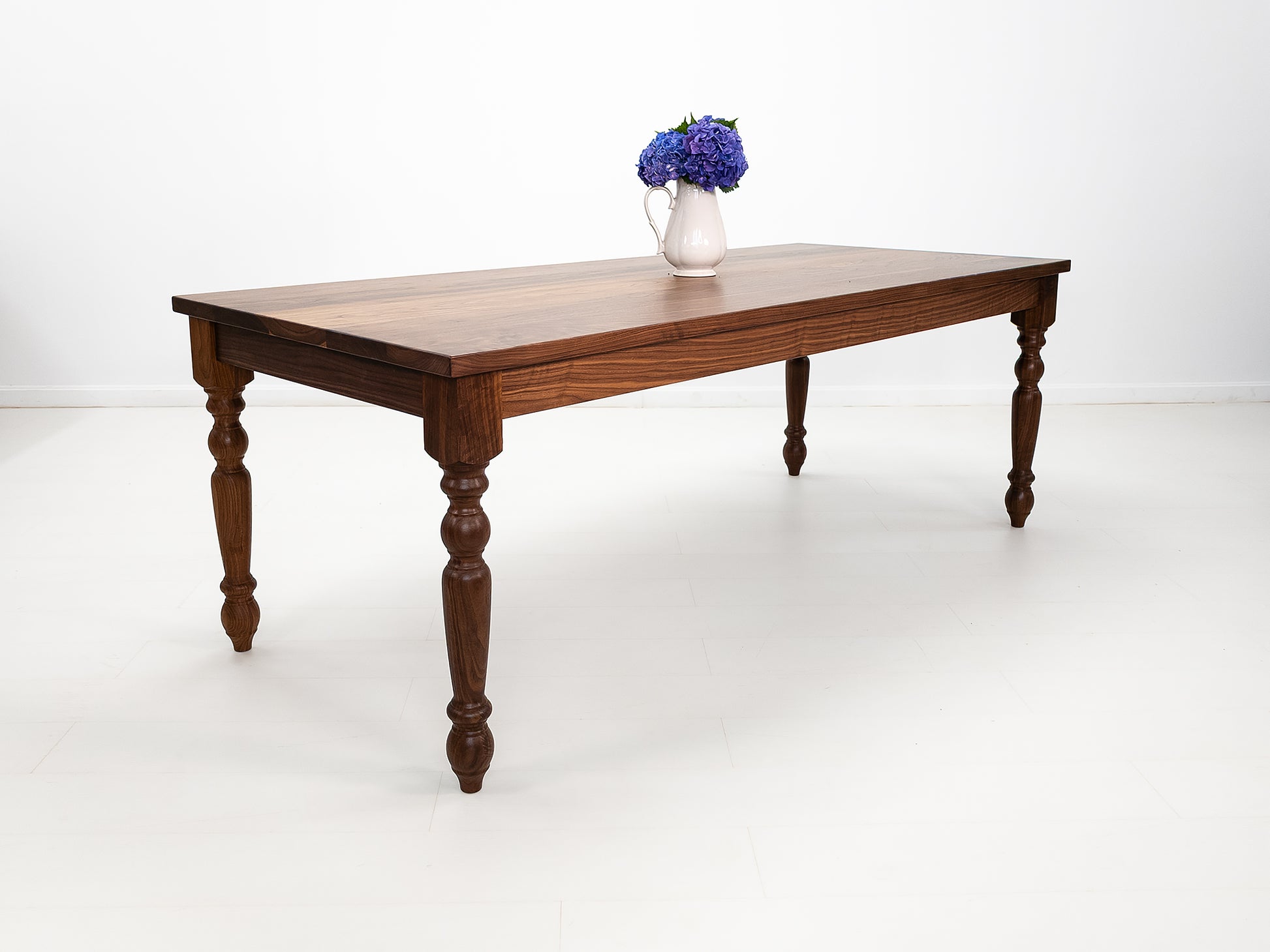 Handcrafted walnut dining table with classic turned legs.
