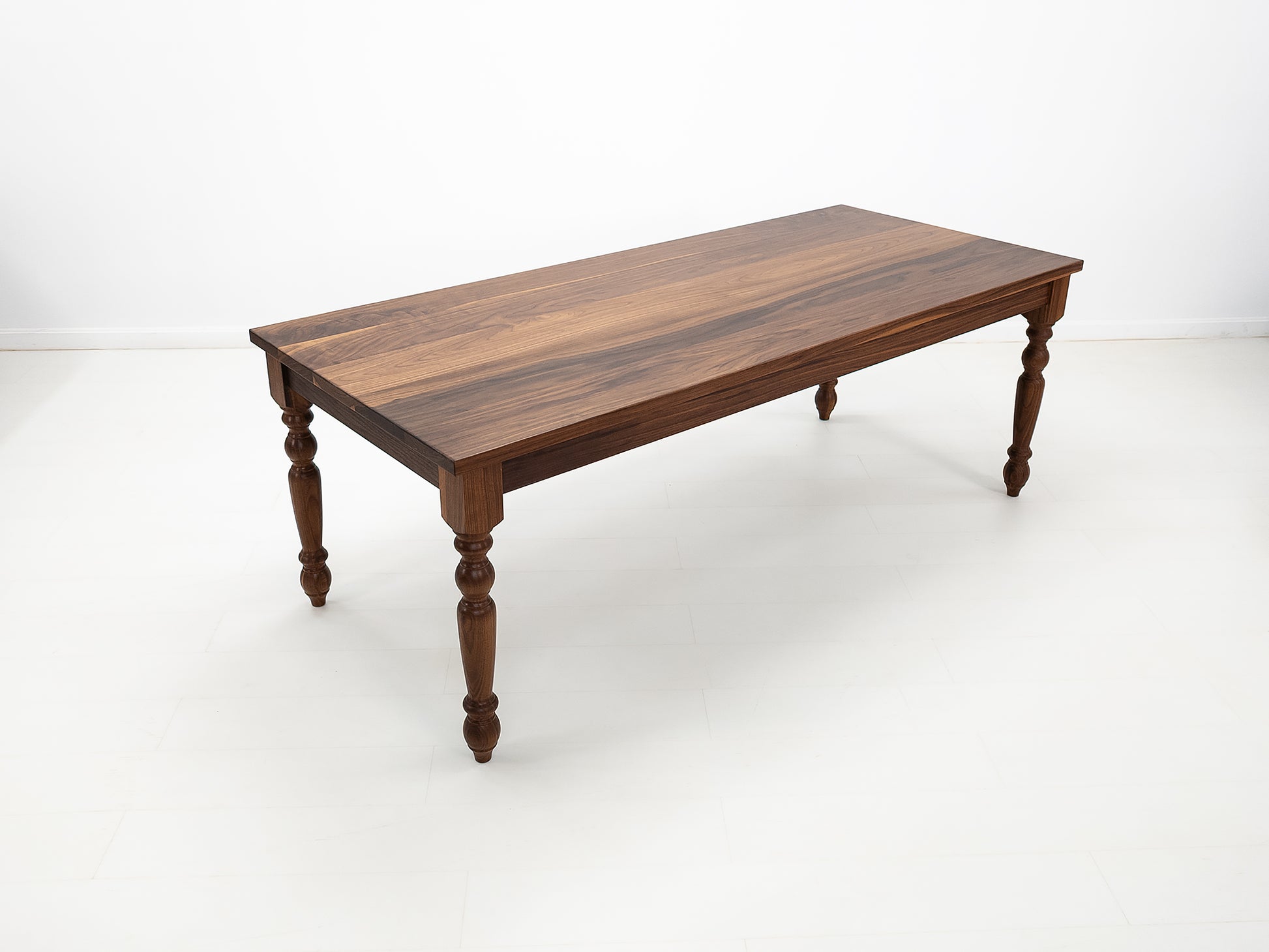 Handcrafted walnut dining table with classic turned legs.