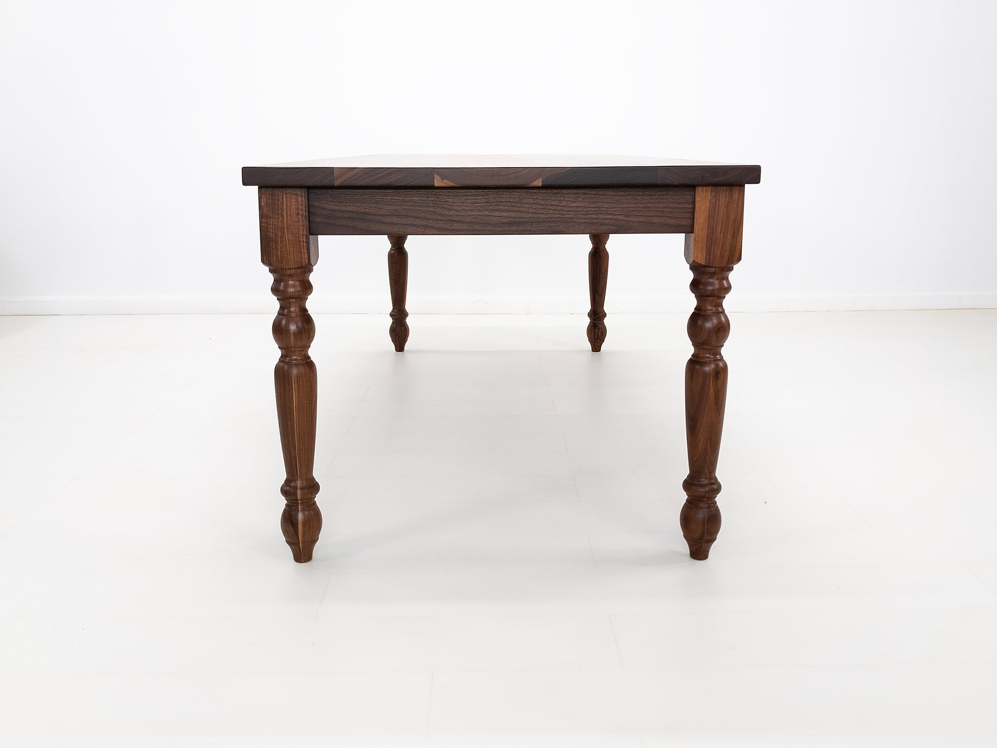 Handcrafted walnut dining table with classic turned legs.