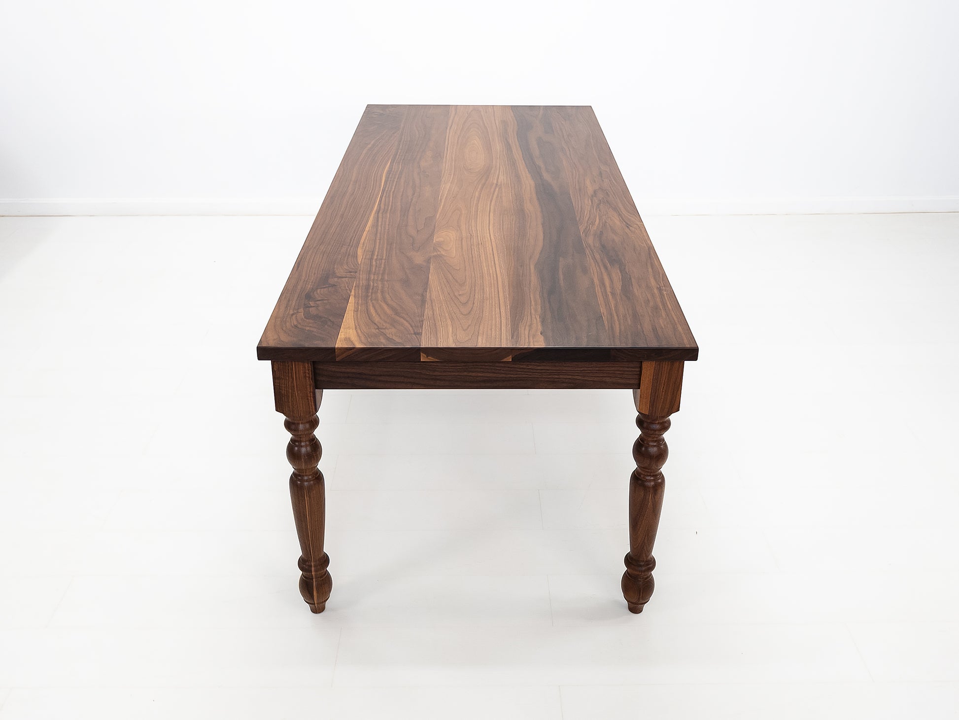 Handcrafted walnut dining table with classic turned legs.