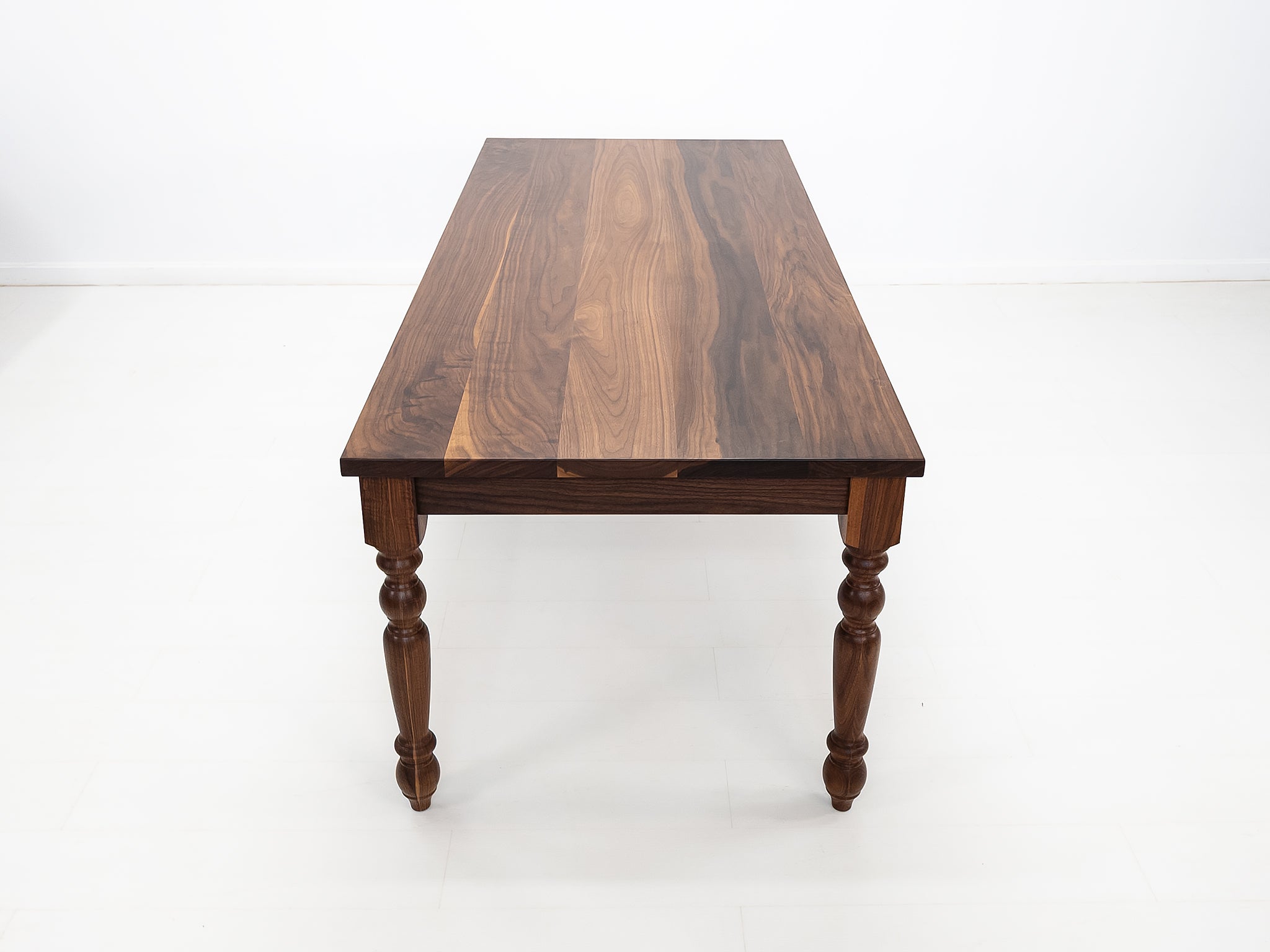 Handcrafted walnut dining table with classic turned legs.