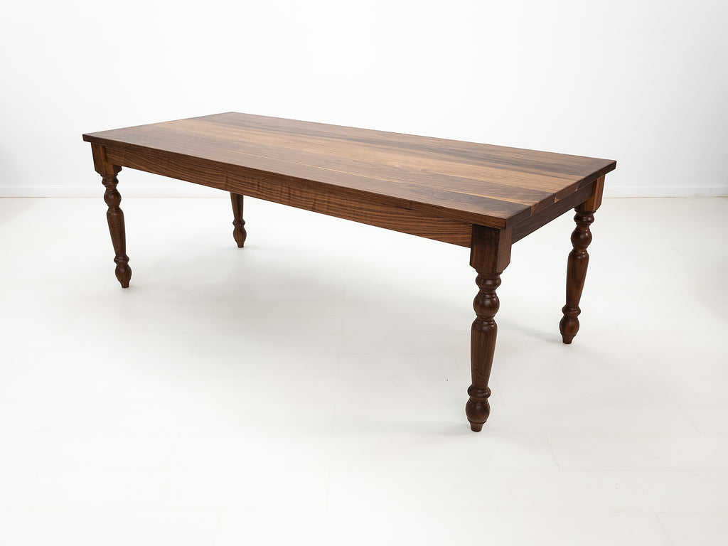 Handcrafted walnut dining table with classic turned legs.