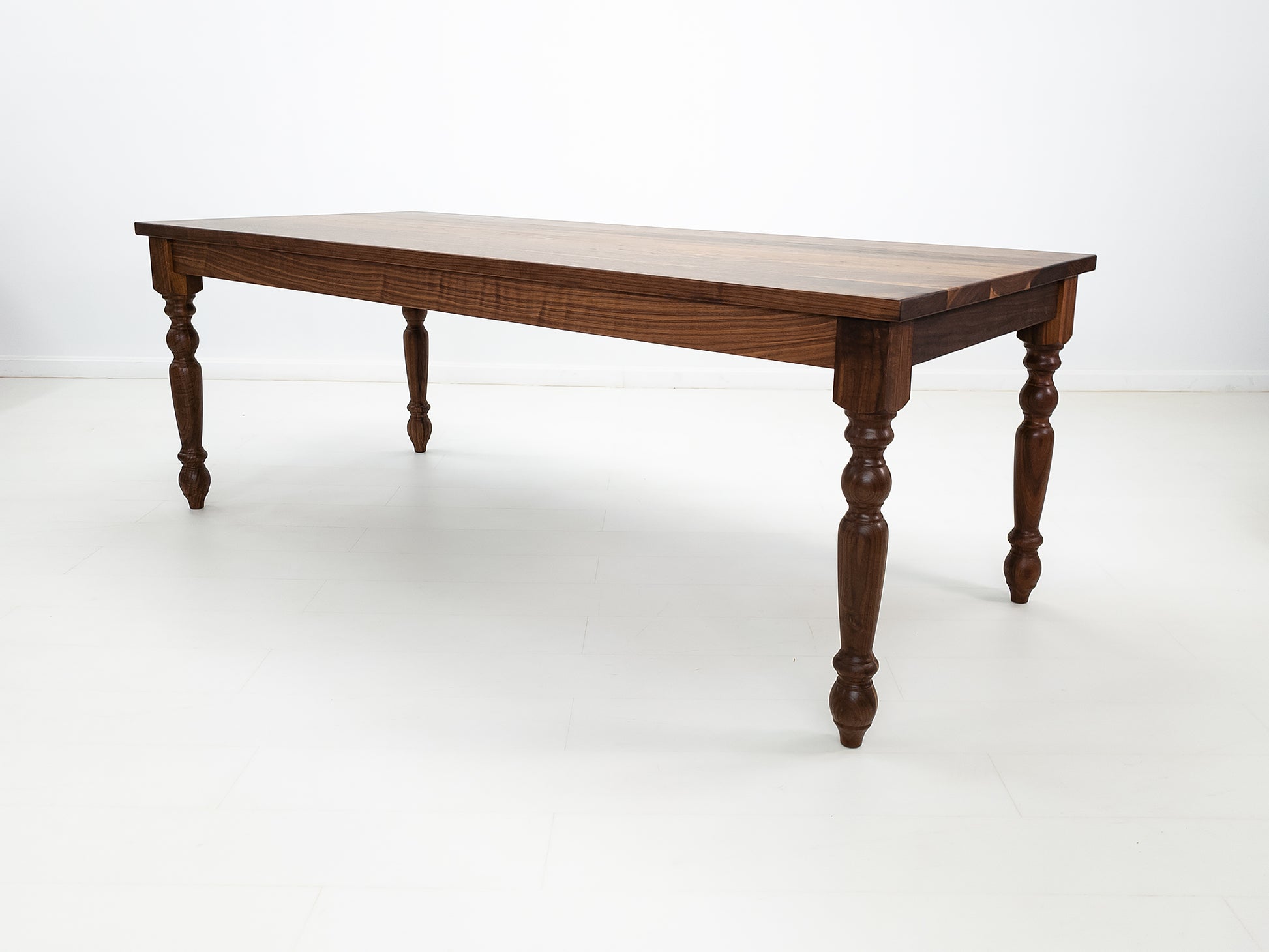 Handcrafted walnut dining table with classic turned legs.