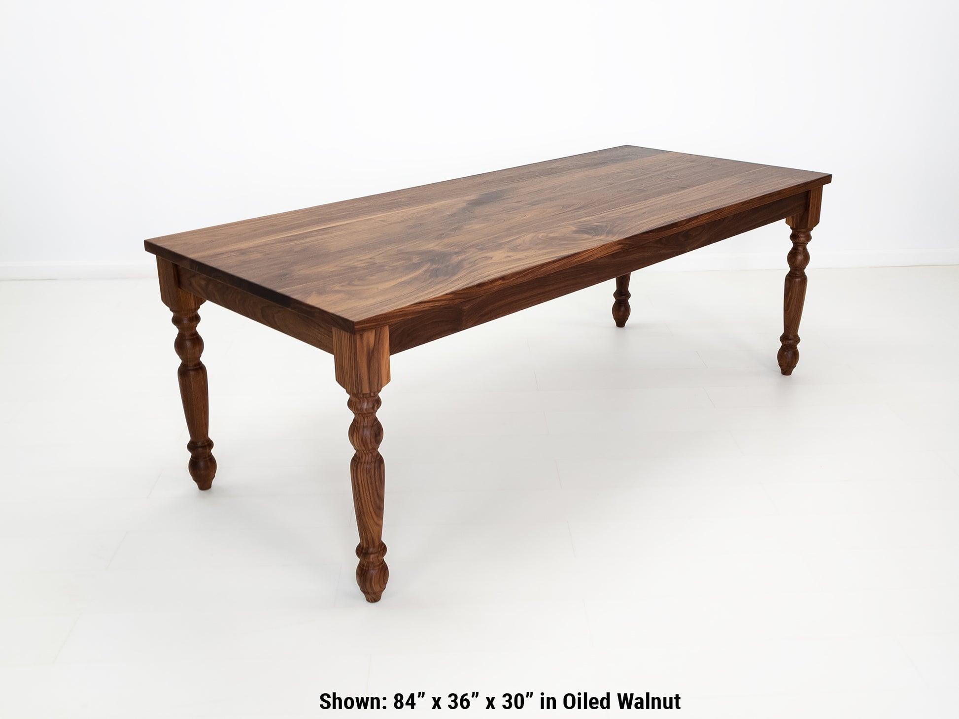 Tess dining table in solid oiled walnut with turned legs and plank-style top.