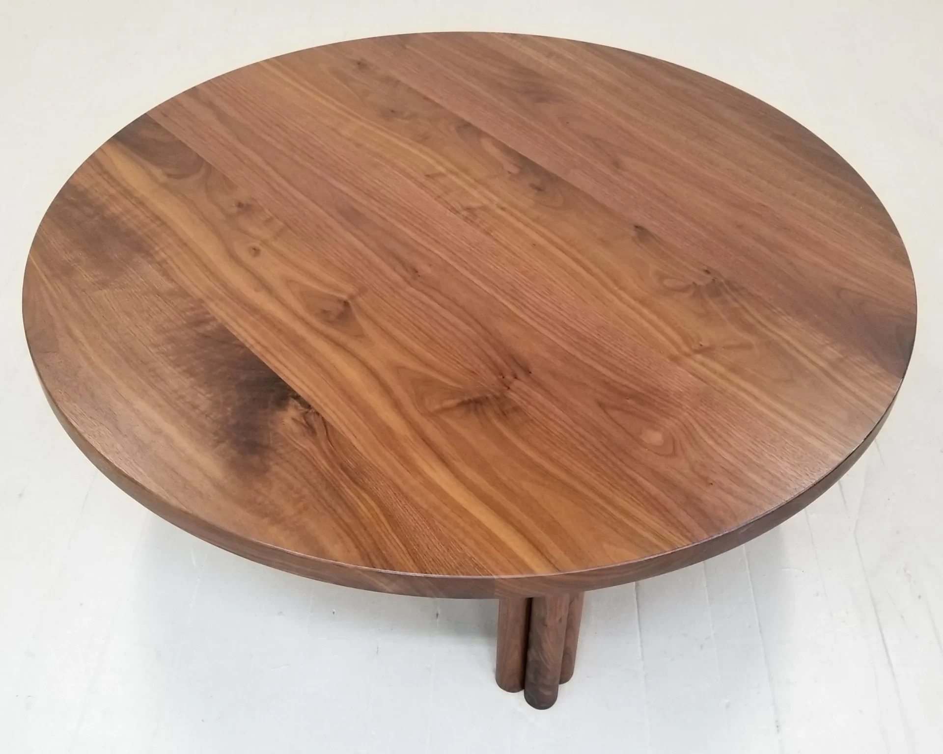 A wooden round coffee table with four legs on top of it.