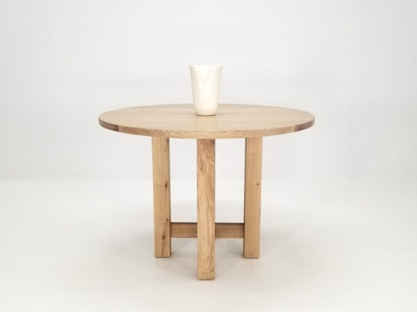A OTTO Round Dining Table with a vase on top.