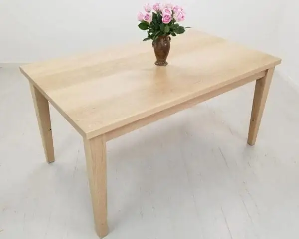 A tapered leg dining table with a vase and flowers on top of it.