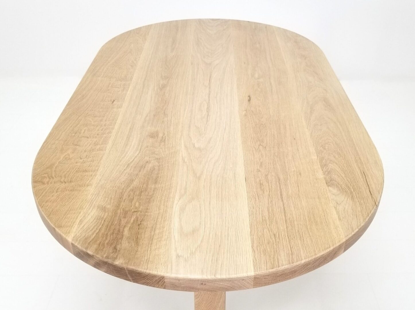 A close up of a oval top trestle dining table with a round top and two legs.