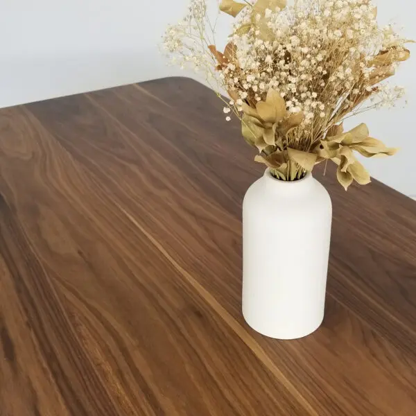 A wooden table with a vase on top of it.