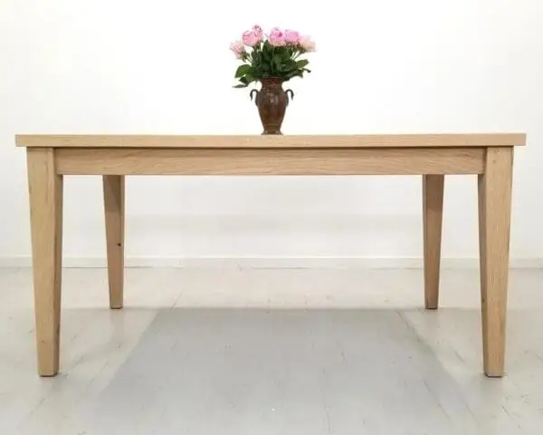 A tapered leg dining table with a vase and flowers on top of it.