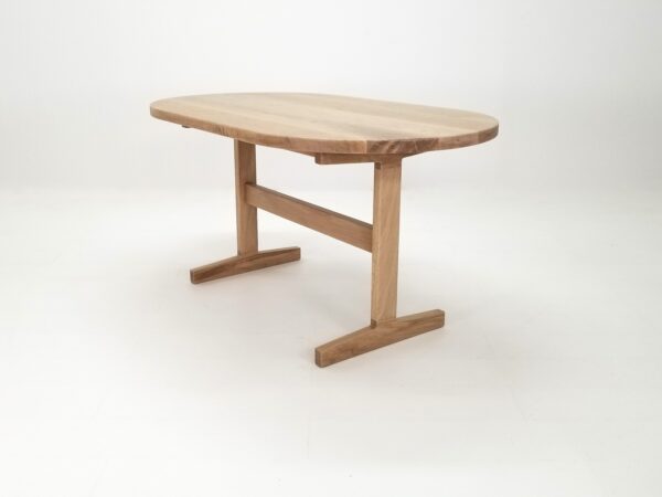 A oval top trestle dining table with a round top and two legs.