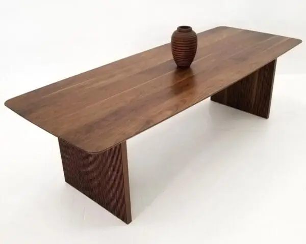 A walnut wooden table with ribbed legs and a vase on top.